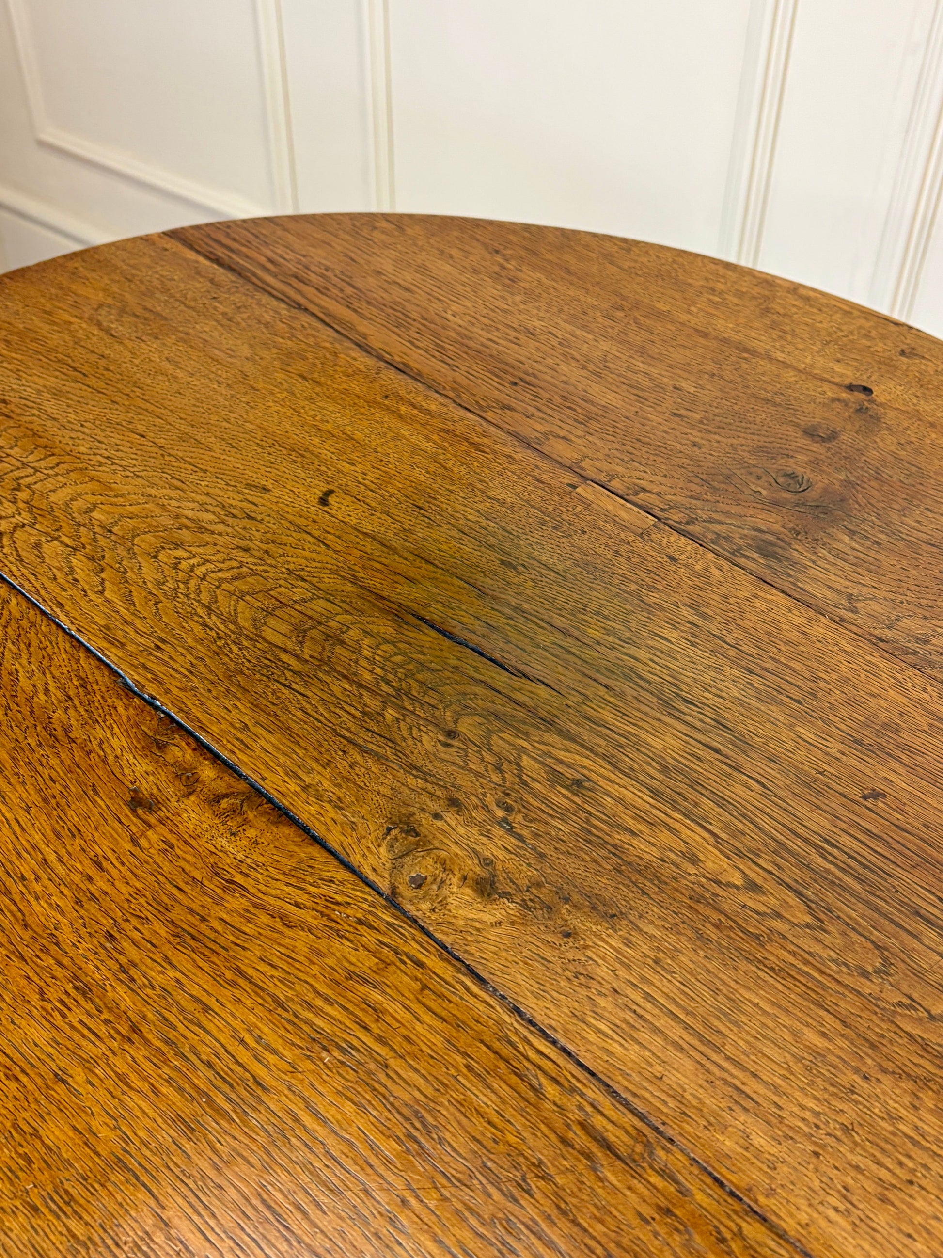 Antique Georgian oak tripod tilt-top table with oval top and tripod base in light oak finish.