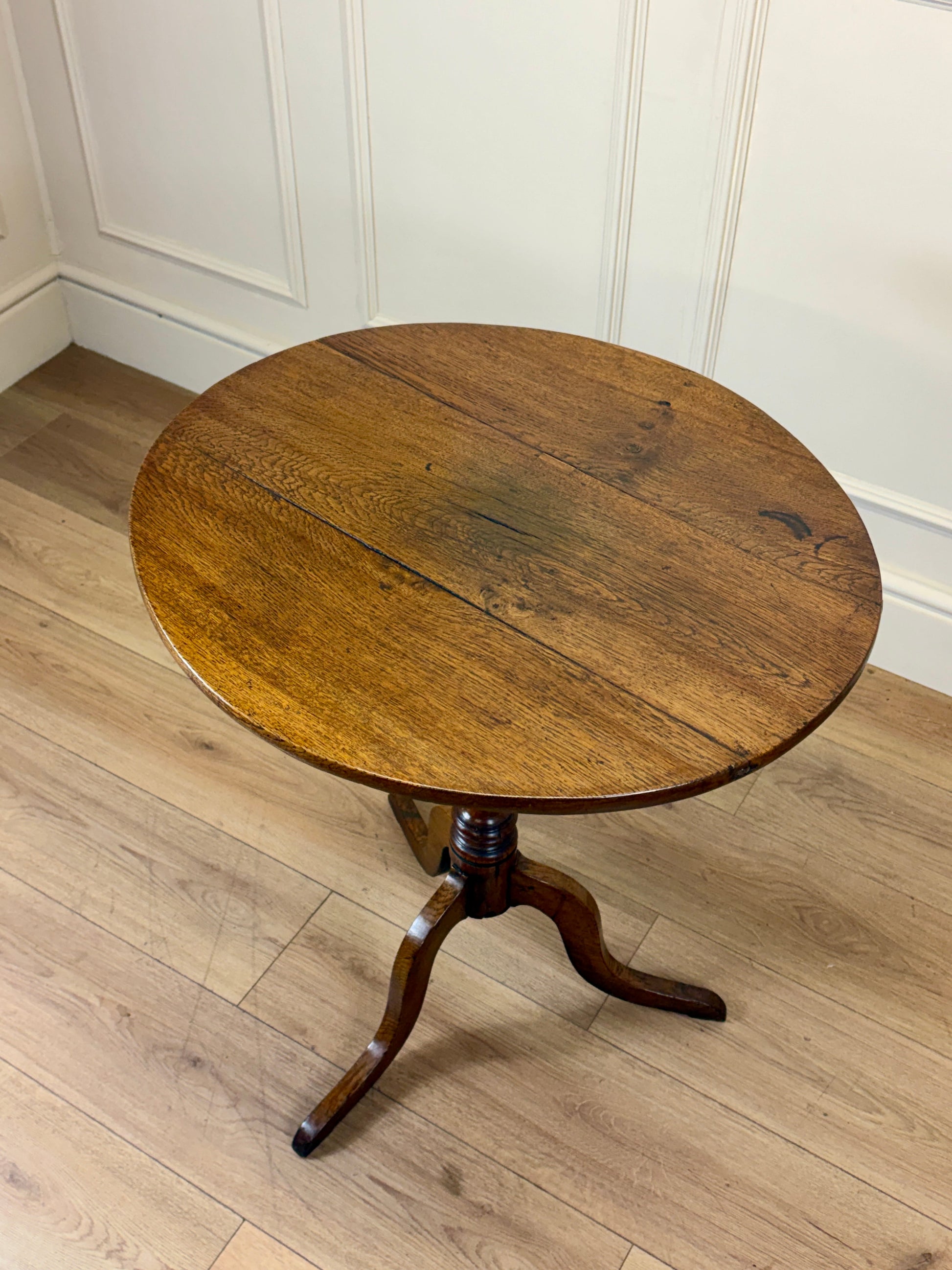 Antique Georgian oak tripod tilt-top table with oval top and tripod base in light oak finish.