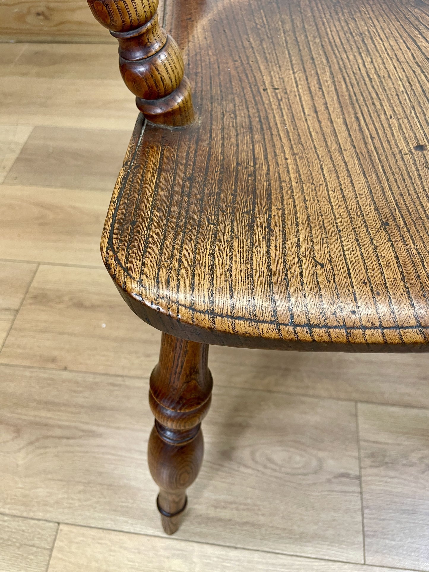 Wooden chair seat with a visible grain pattern on a wooden floor.