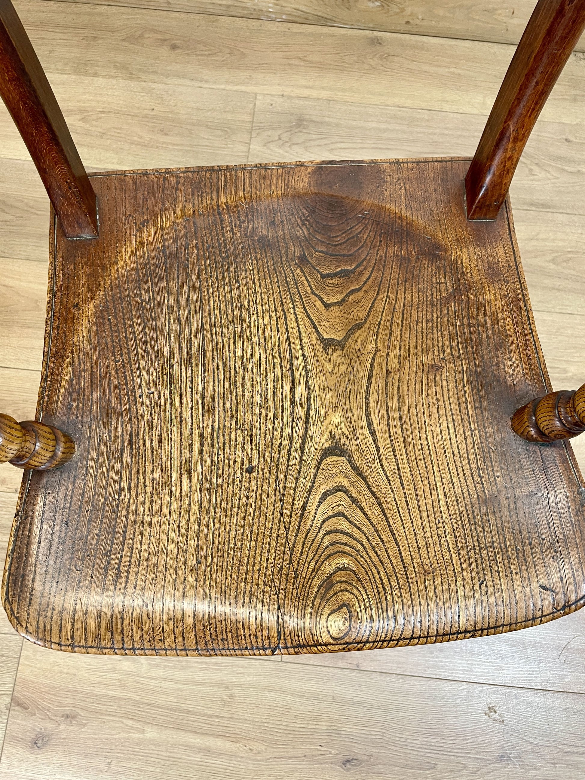 Wooden chair seat with visible wear on a wooden floor