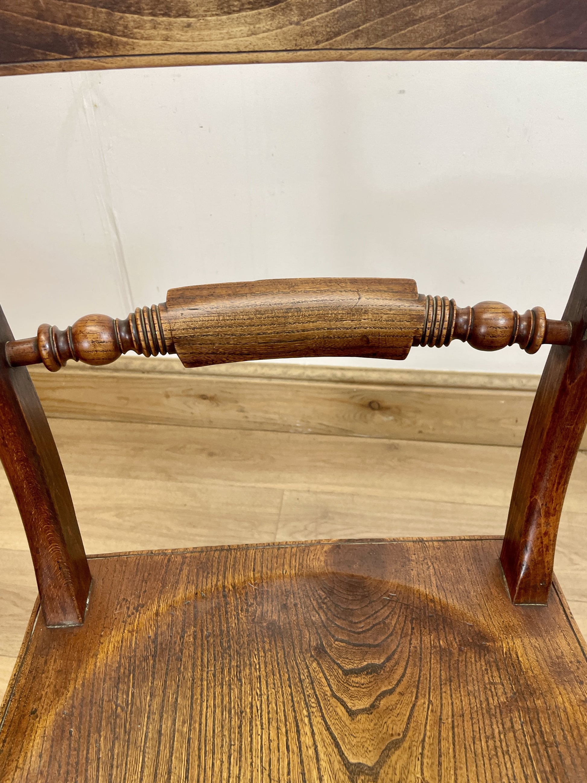 Close-up of a wooden chair with intricate design on a light wood floor.