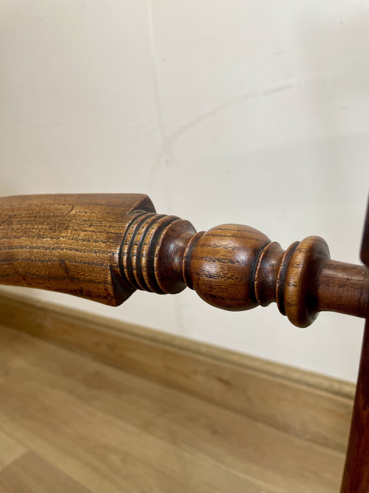 Close-up of a wooden stair baluster against a plain wall.
