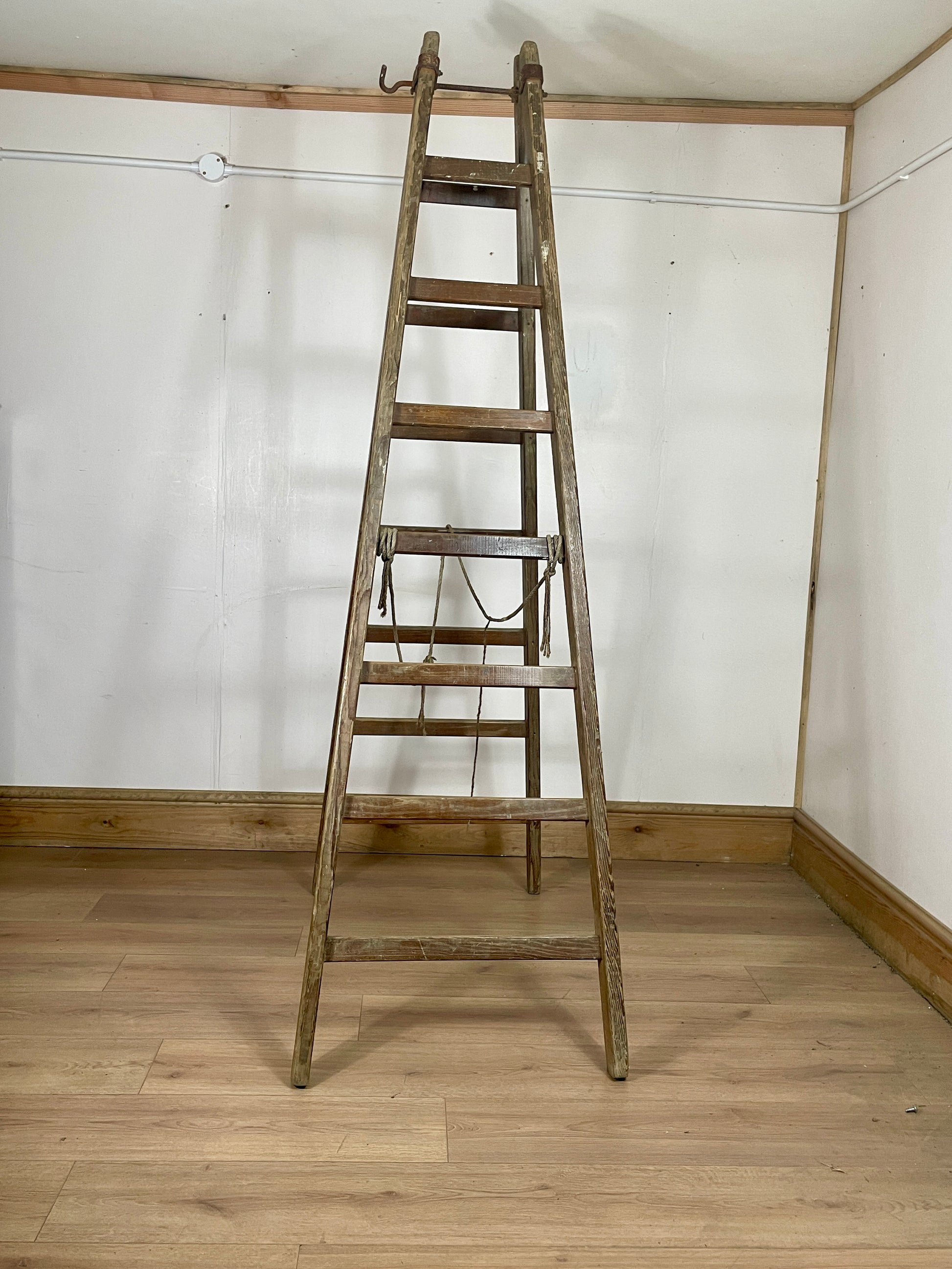 Wooden ladder against a white wall with wooden floor