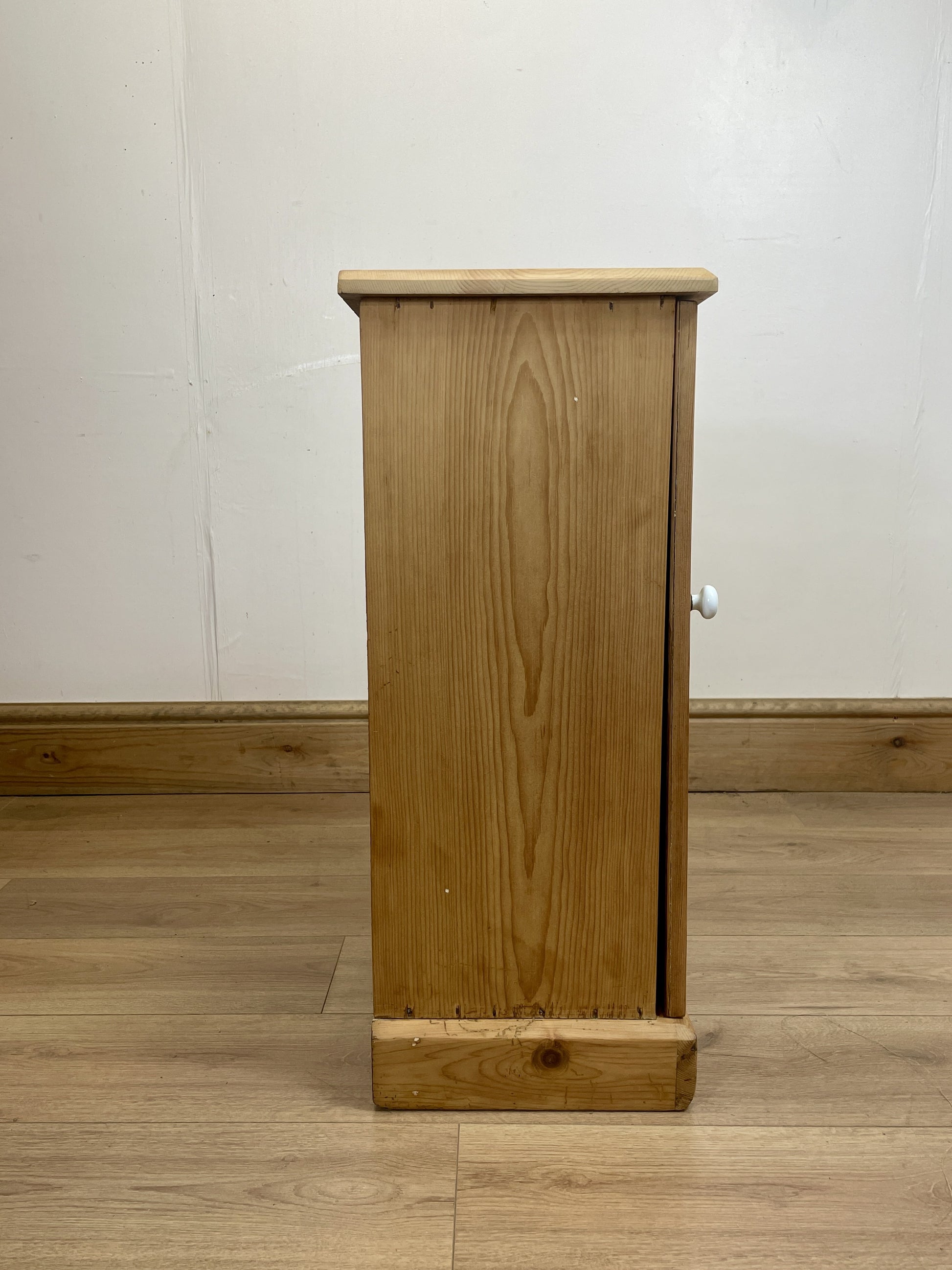 Wooden cabinet on a wooden floor with a white wall background