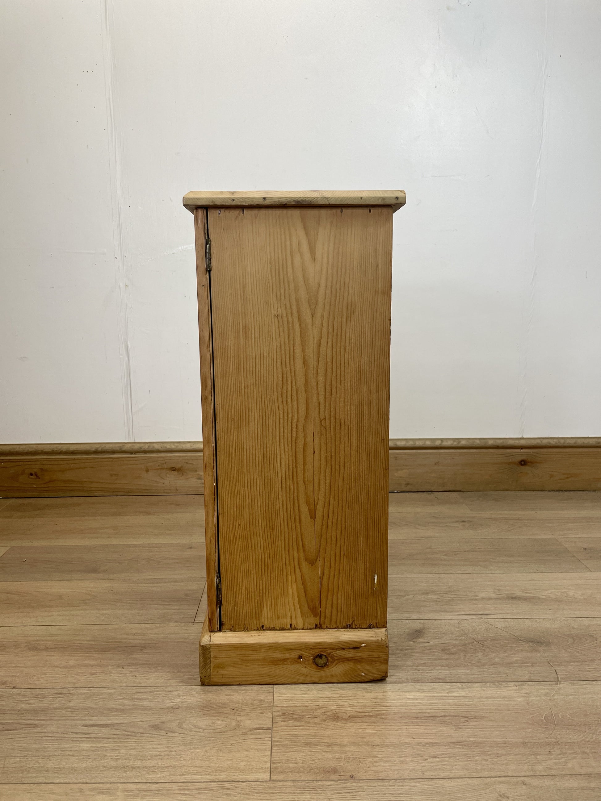 Wooden cabinet on a wooden floor with a white wall background
