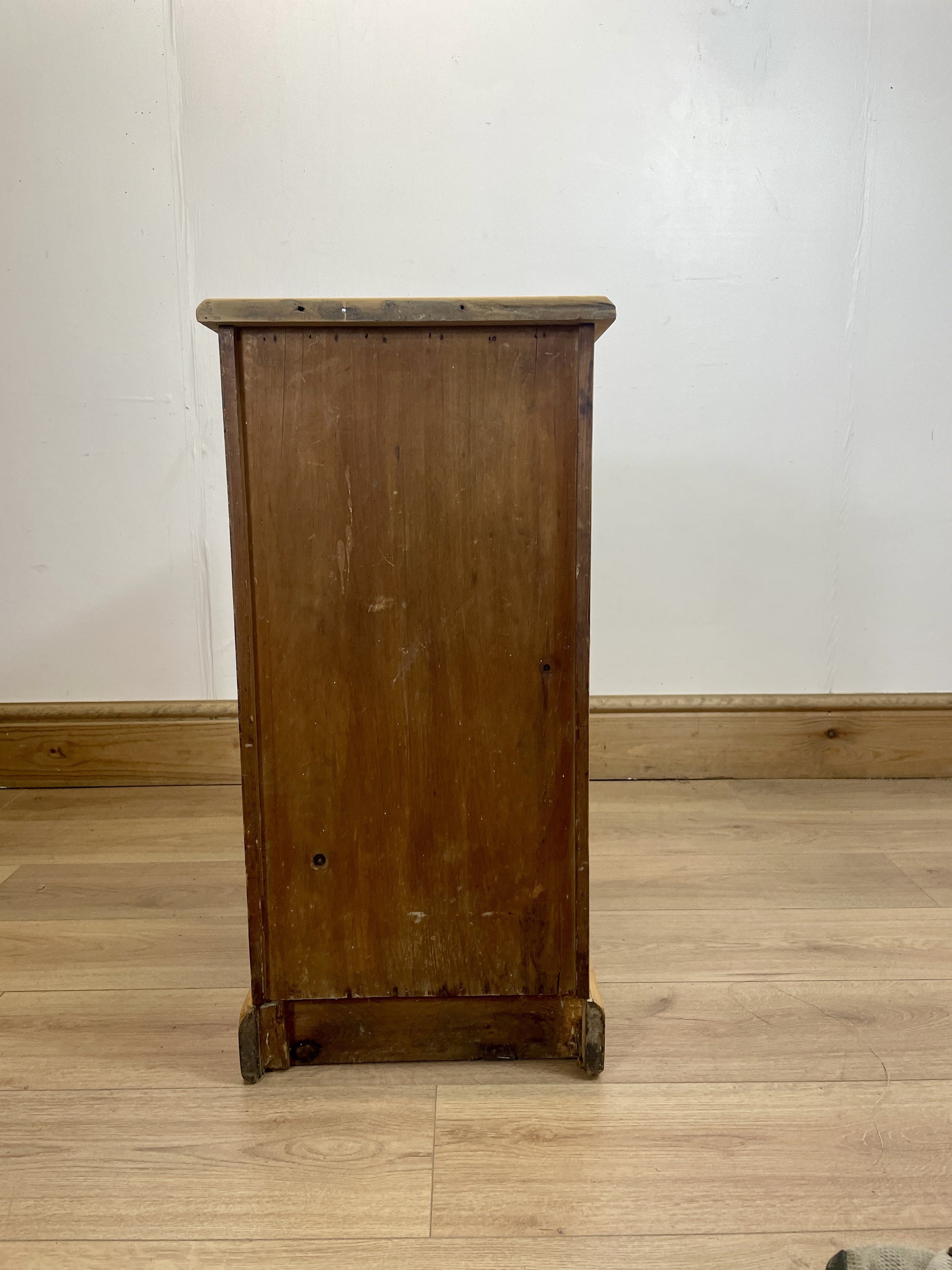 Wooden cabinet on a wooden floor with a white wall background