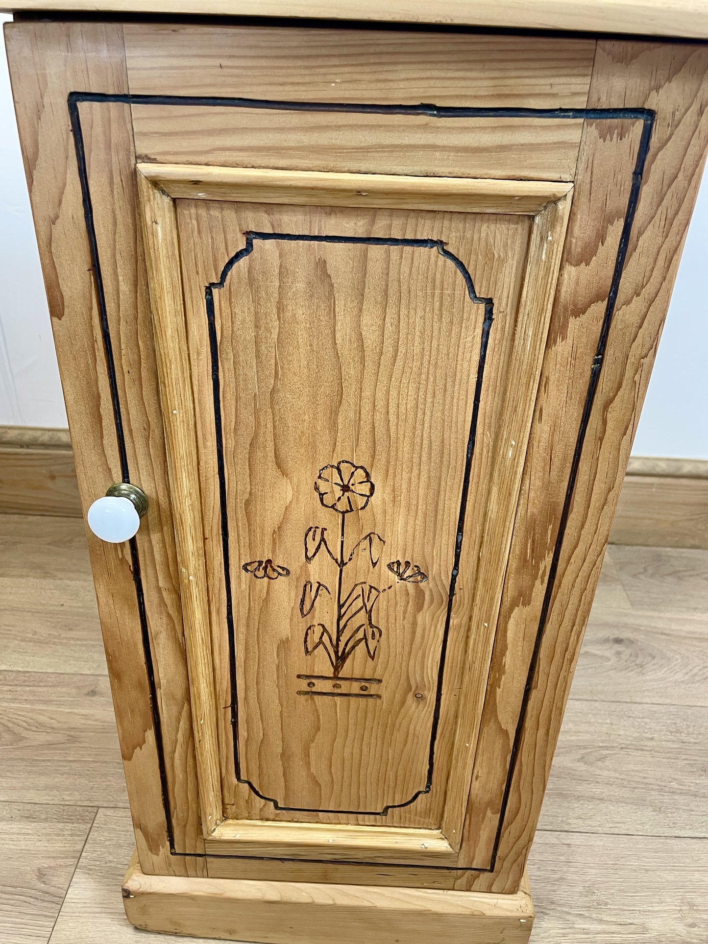 Wooden cabinet with floral engraving on a wooden floor