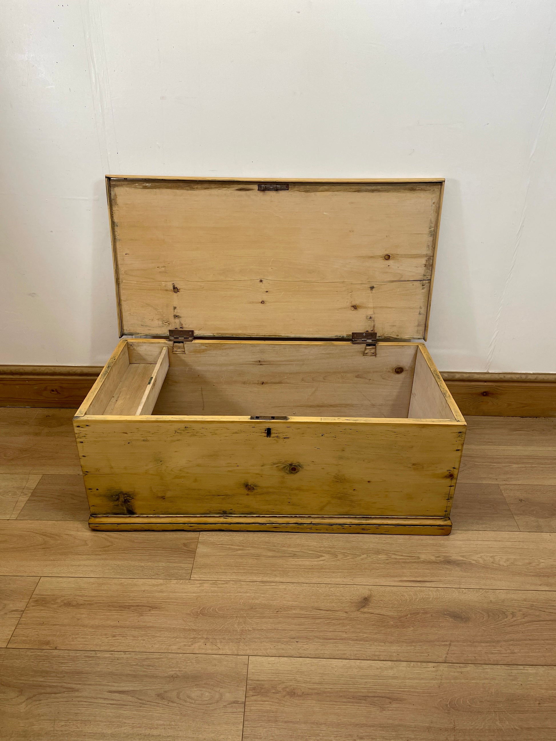 Wooden chest on a wooden floor with a white wall background