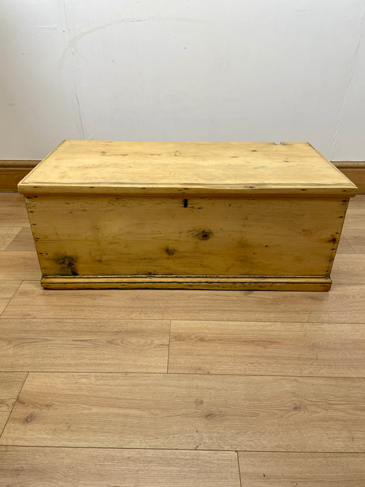 Wooden storage chest on a wooden floor with a white wall background