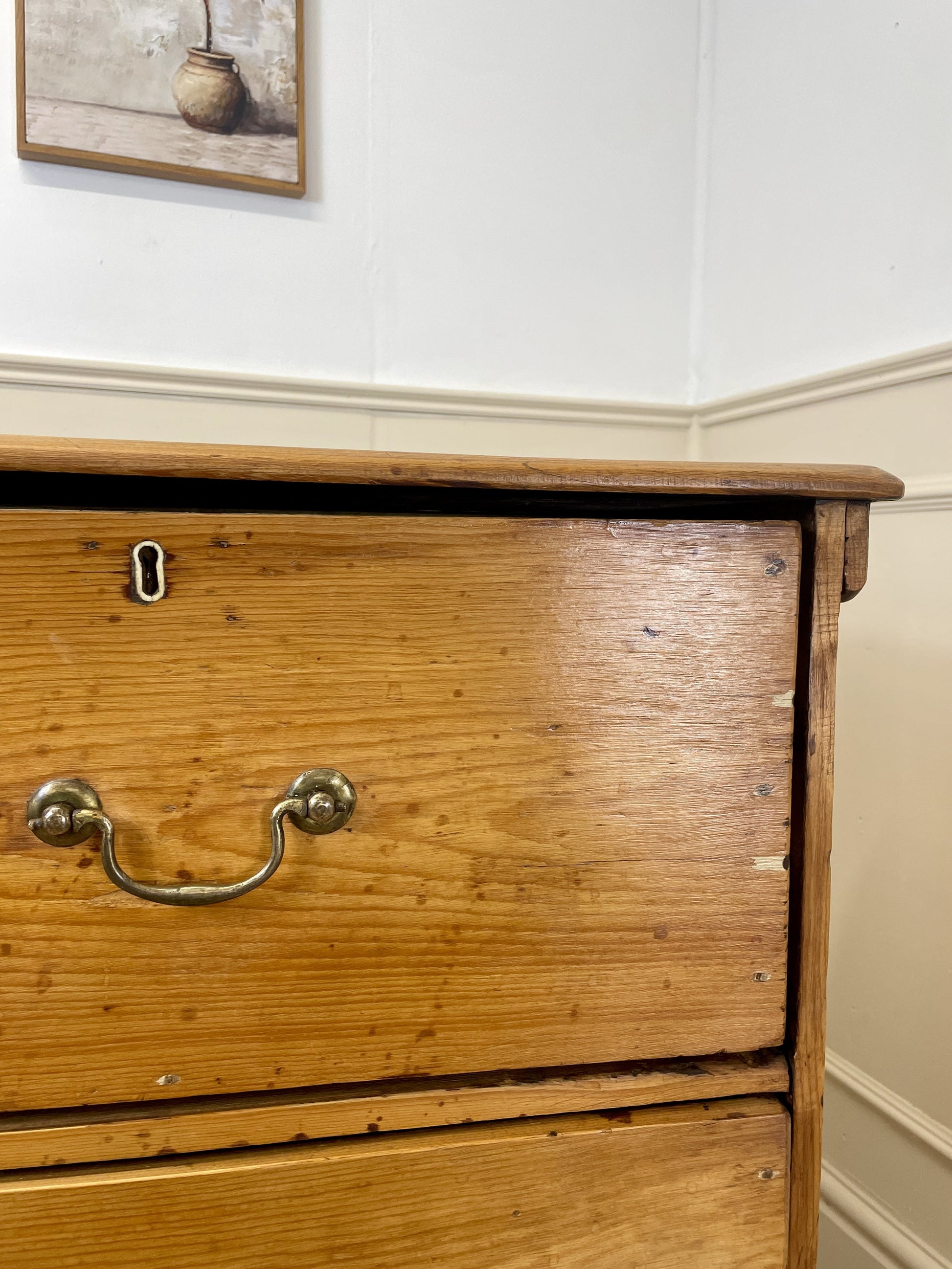 Wooden dresser with brass handles against a white wall