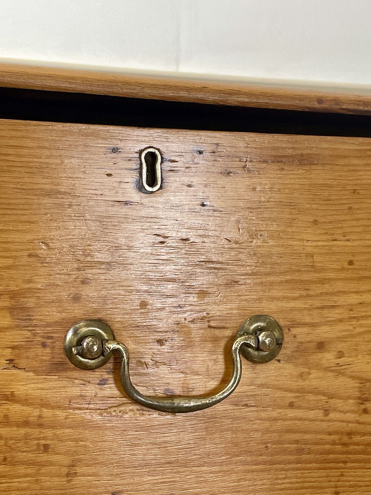 Wooden drawer with brass handle and keyhole on a white background