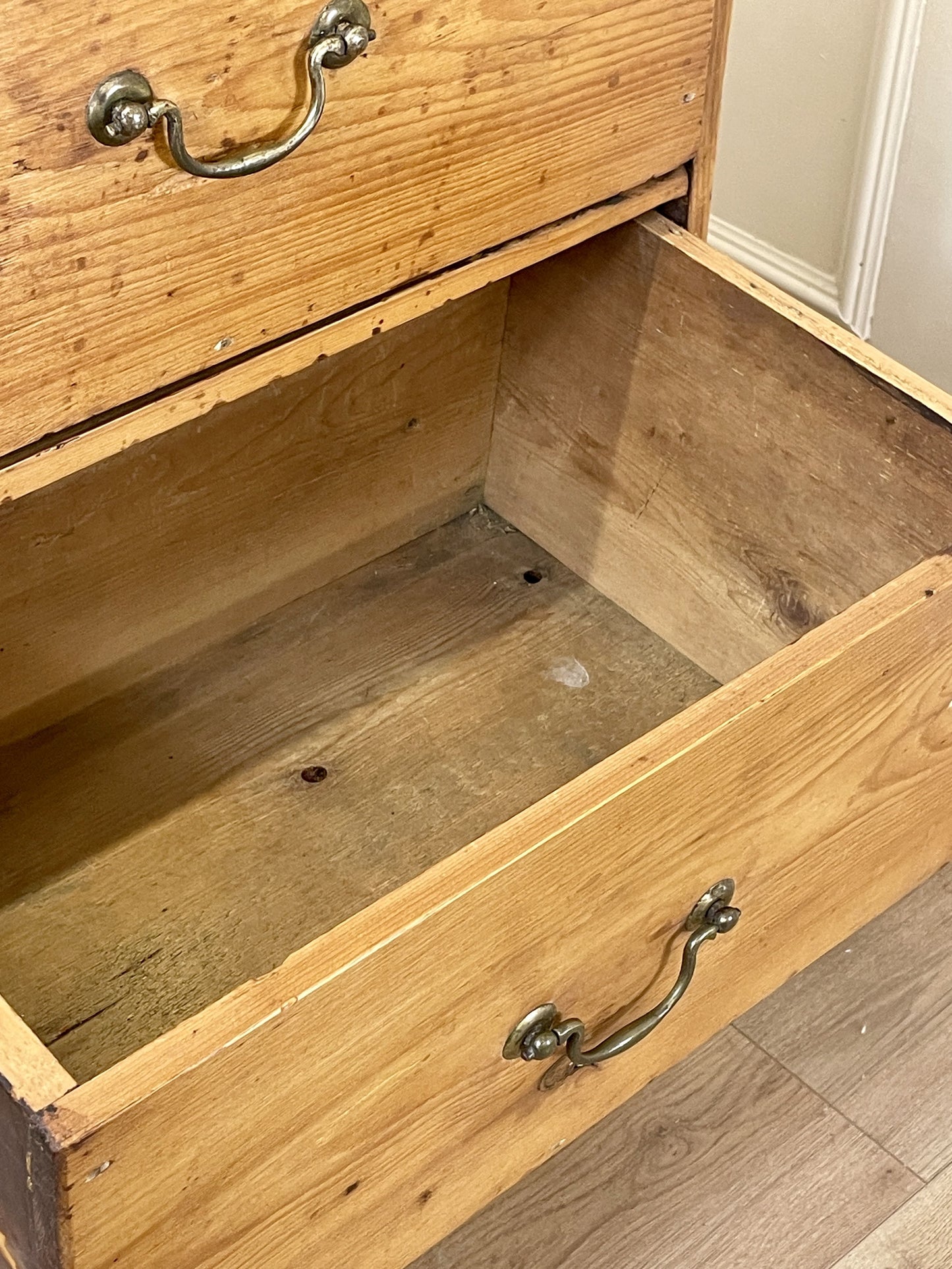 Wooden drawer with metal handles on a wooden floor.