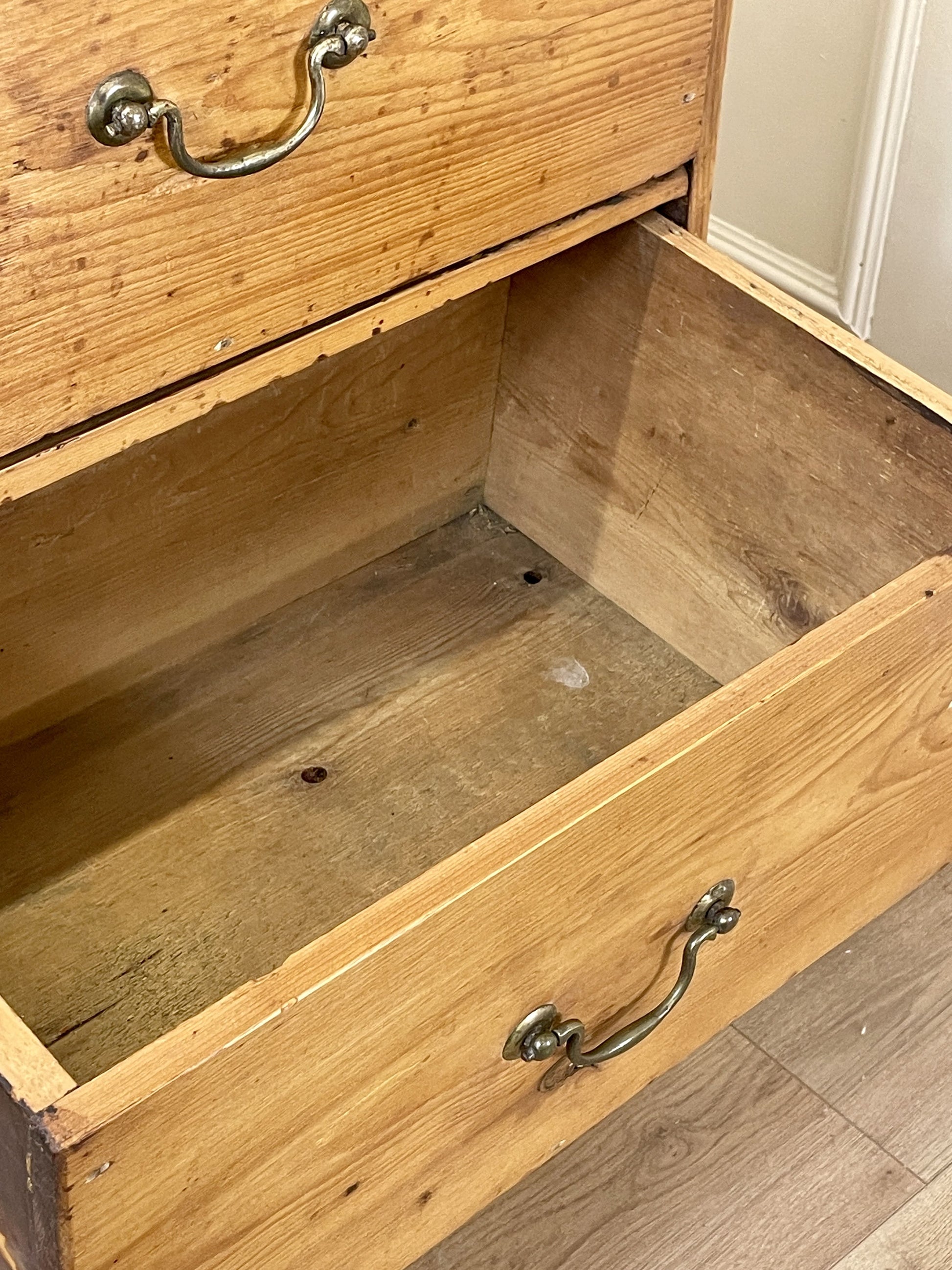 Wooden drawer with metal handles on a wooden floor.