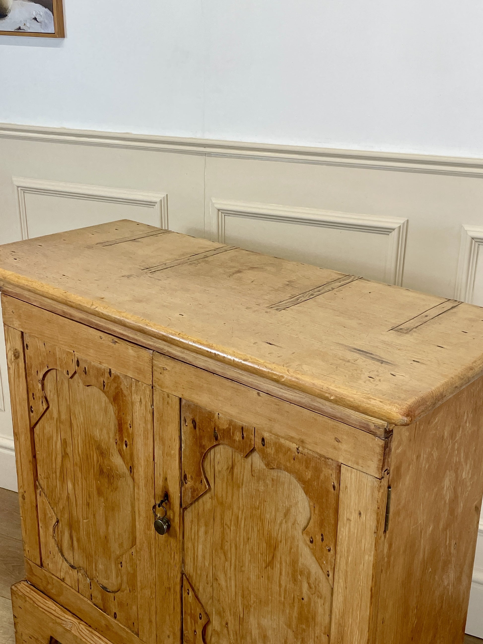 Wooden cabinet with carved details on a white wall background