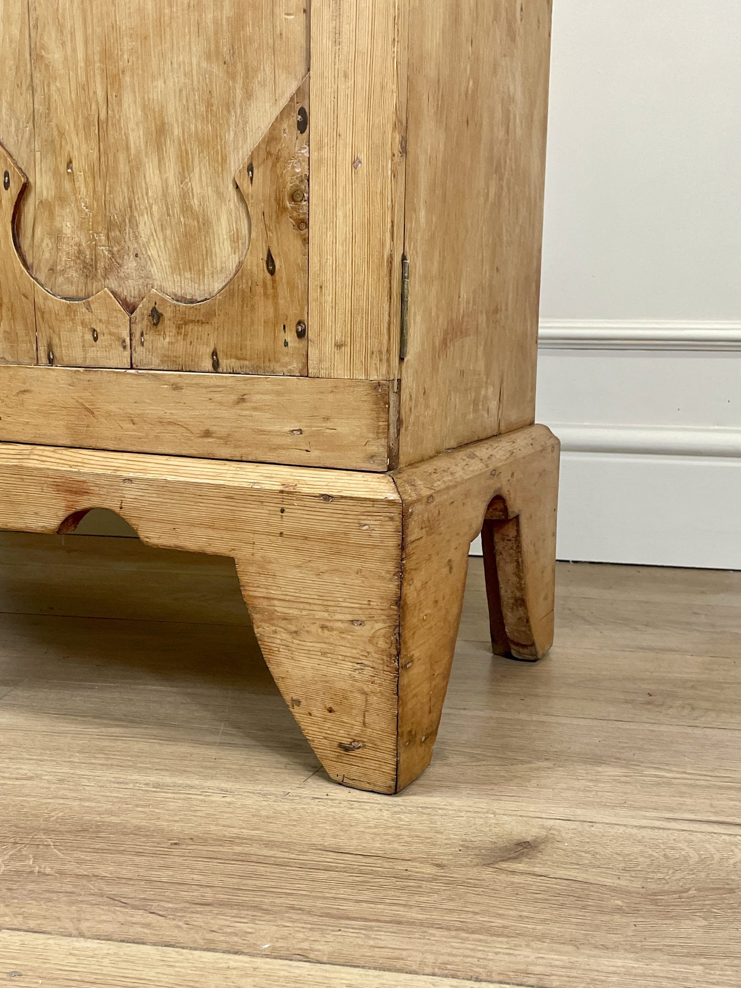 Wooden cabinet with intricate carvings on a wooden floor.