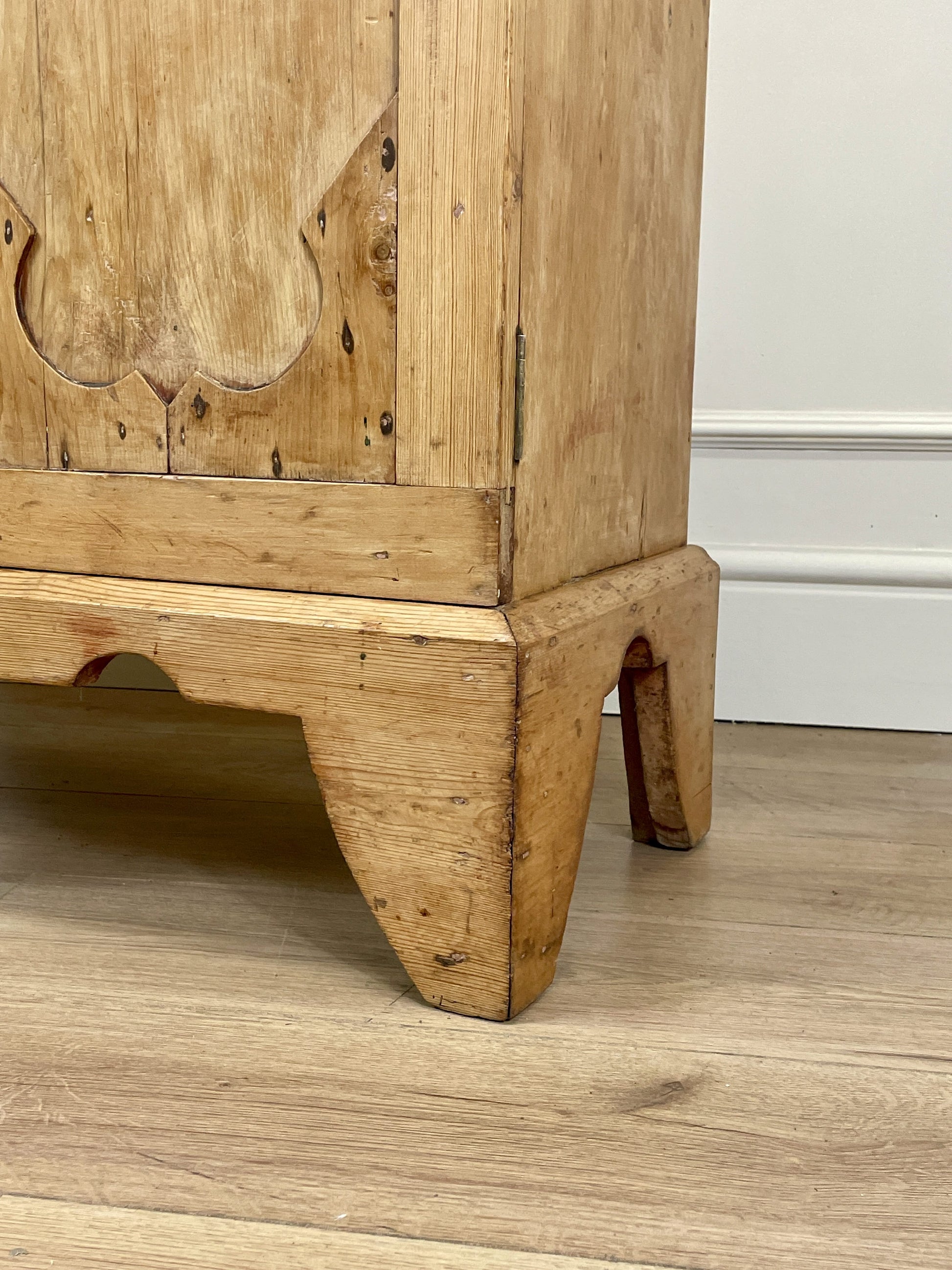 Wooden cabinet with intricate carvings on a wooden floor.