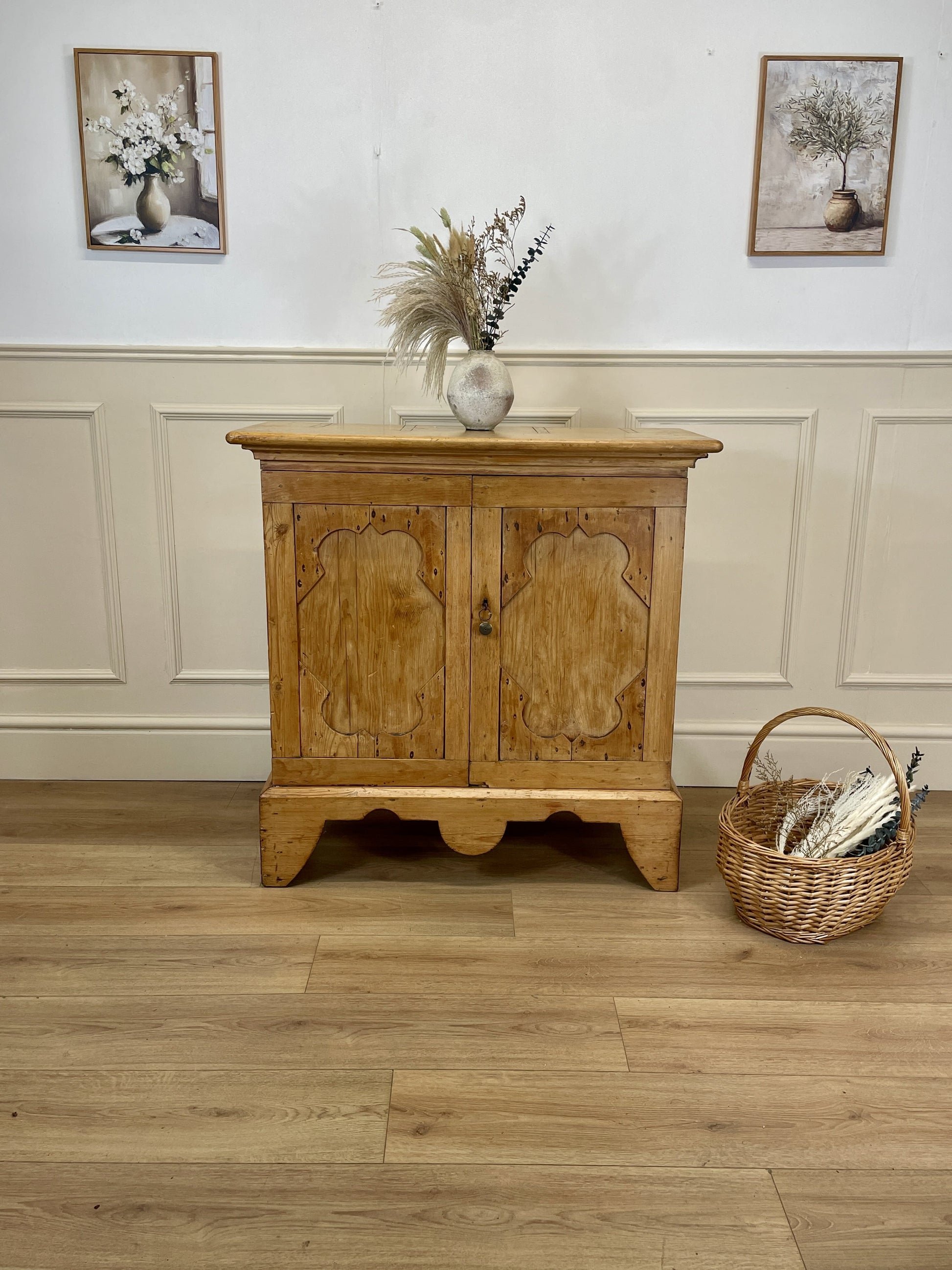 Wooden cabinet with decorative elements on a wooden floor and white wall background