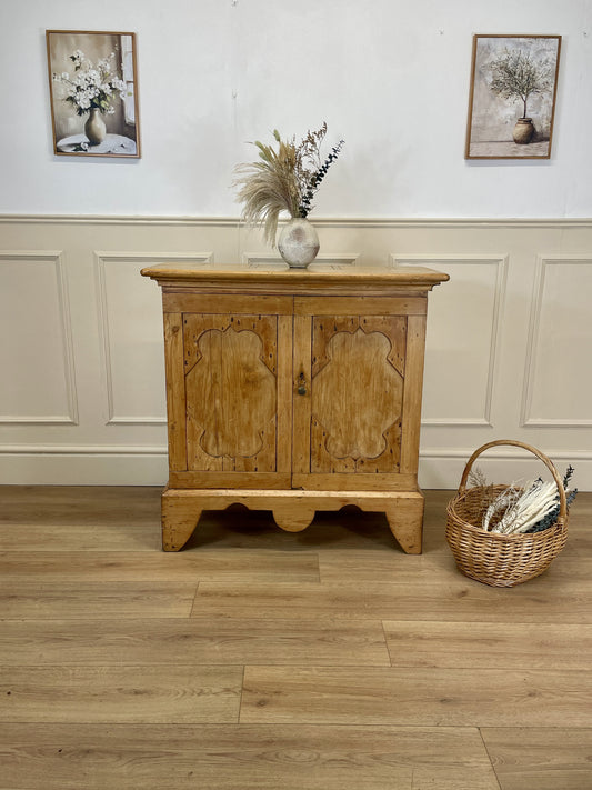 Wooden cabinet with decorative elements on a wooden floor and white wall background