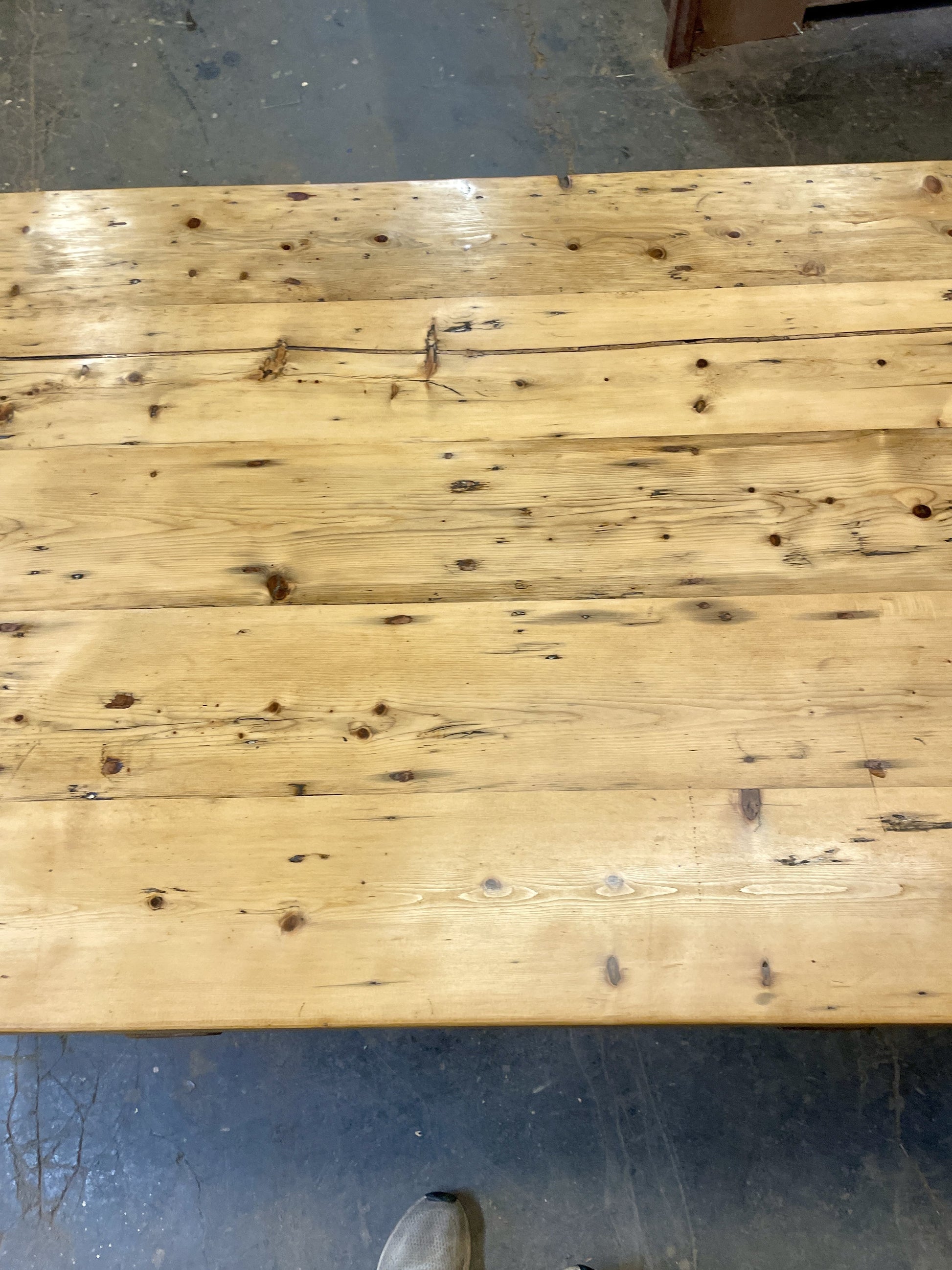 Wooden table with visible grain and knots on a concrete floor.