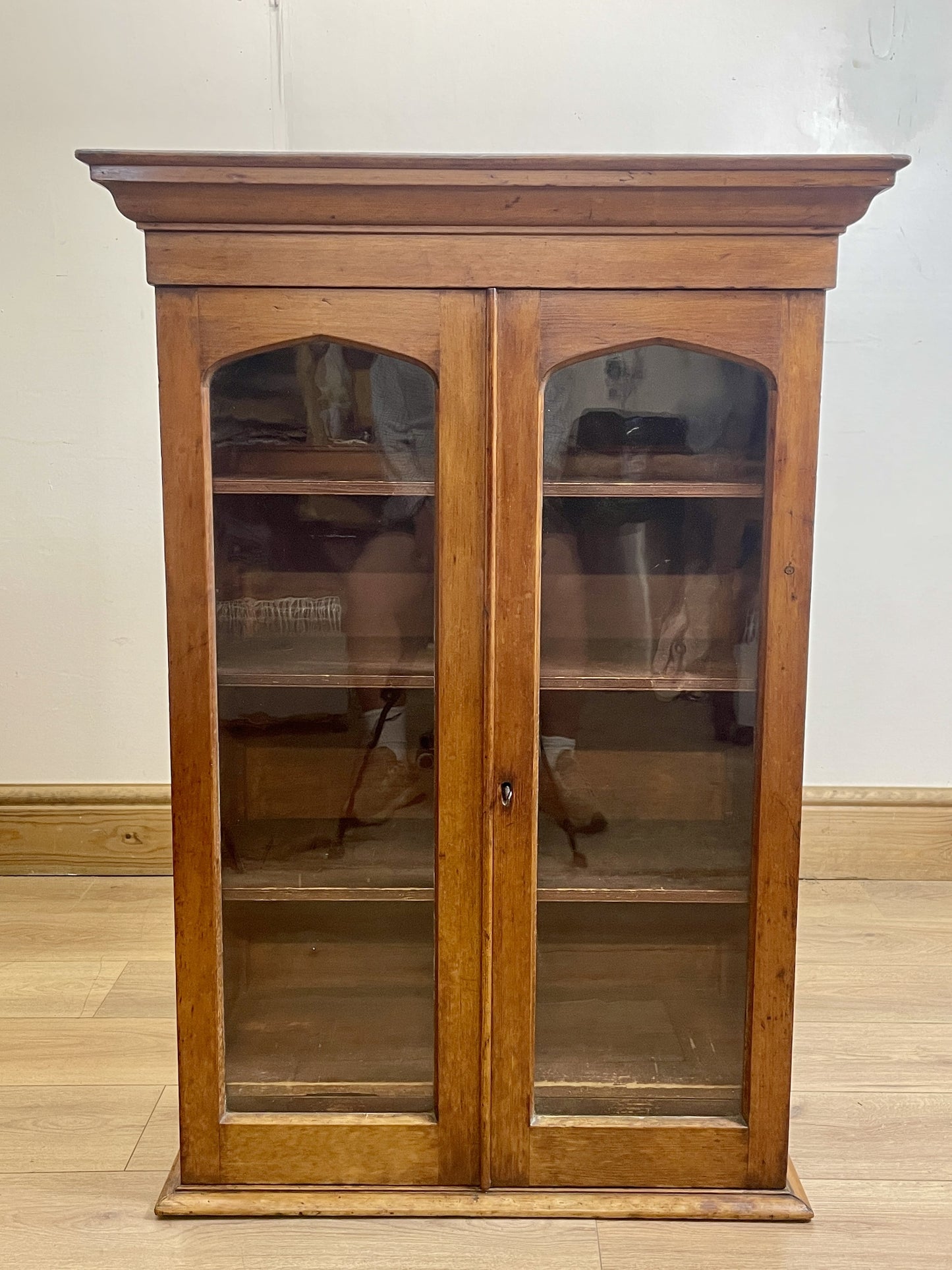 Wooden display cabinet with glass doors on a wooden floor.