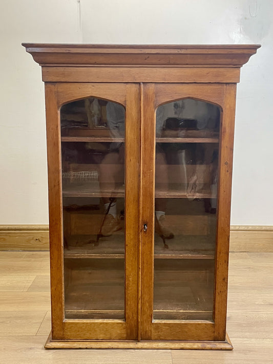 Wooden display cabinet with glass doors on a wooden floor.