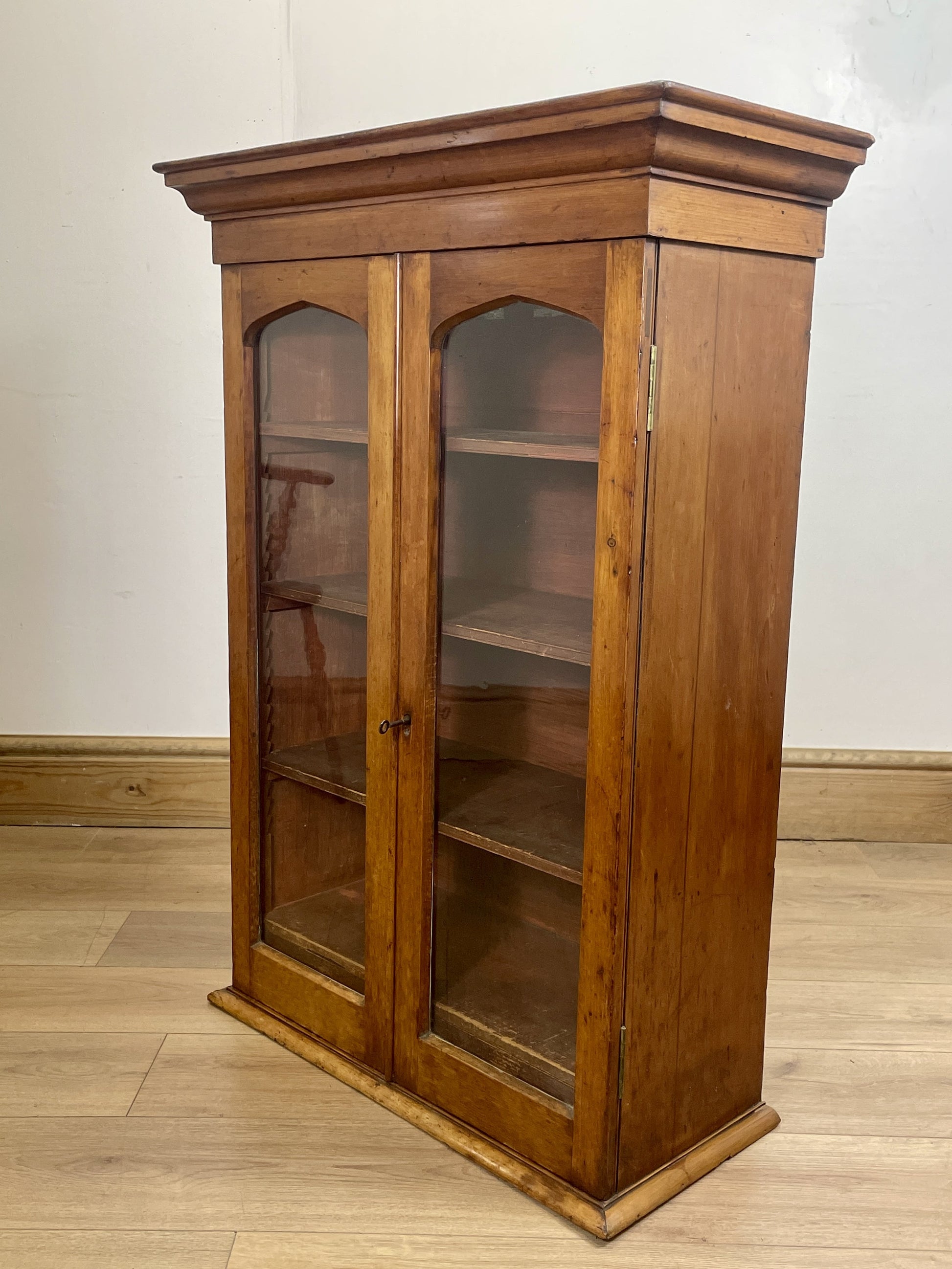 Wooden display cabinet with glass doors on a wooden floor.