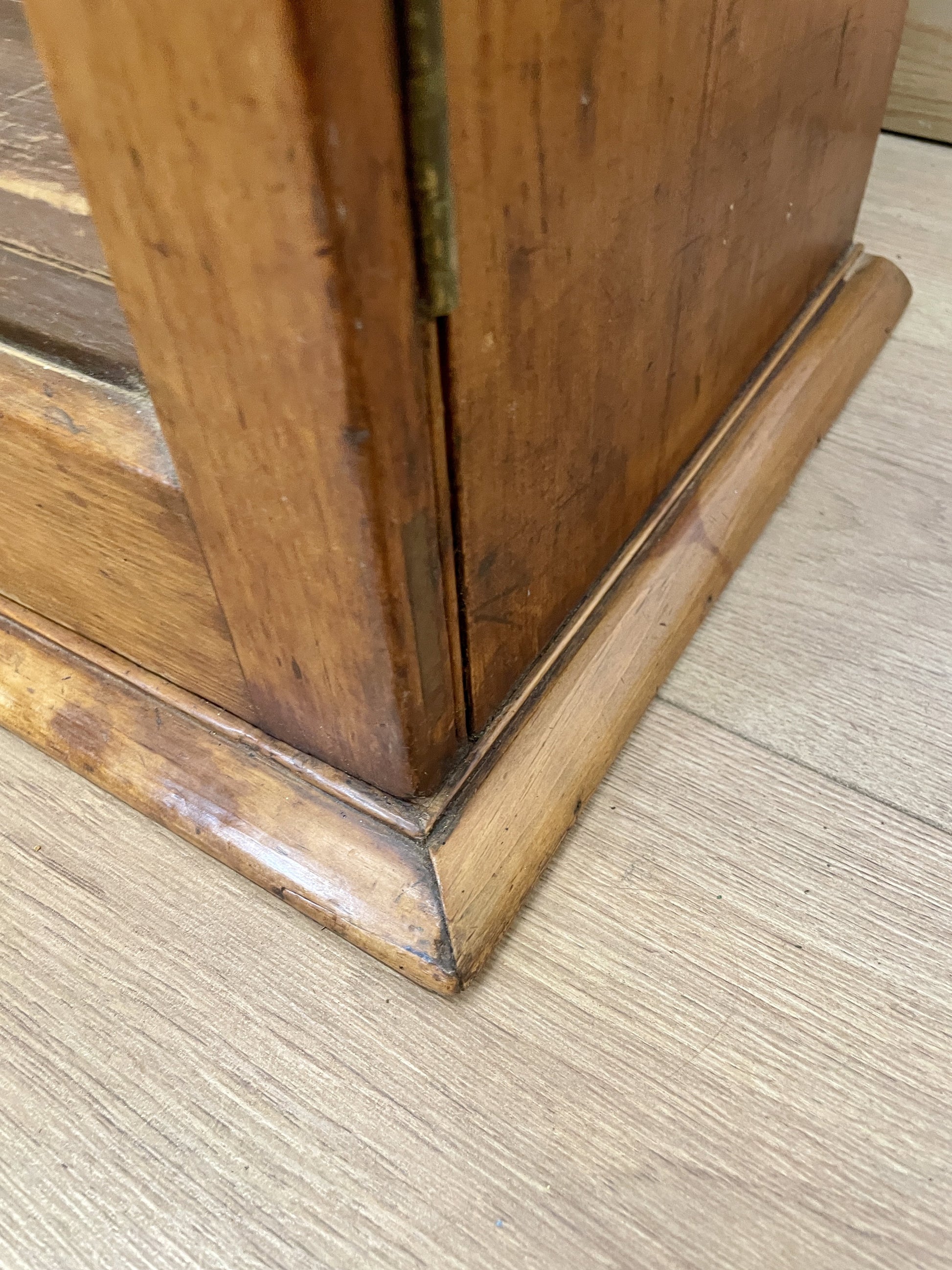 Close-up of a wooden cabinet corner on a carpeted floor