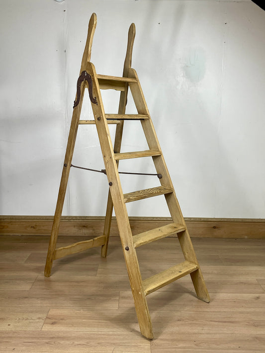 Wooden ladder against a white wall on a wooden floor