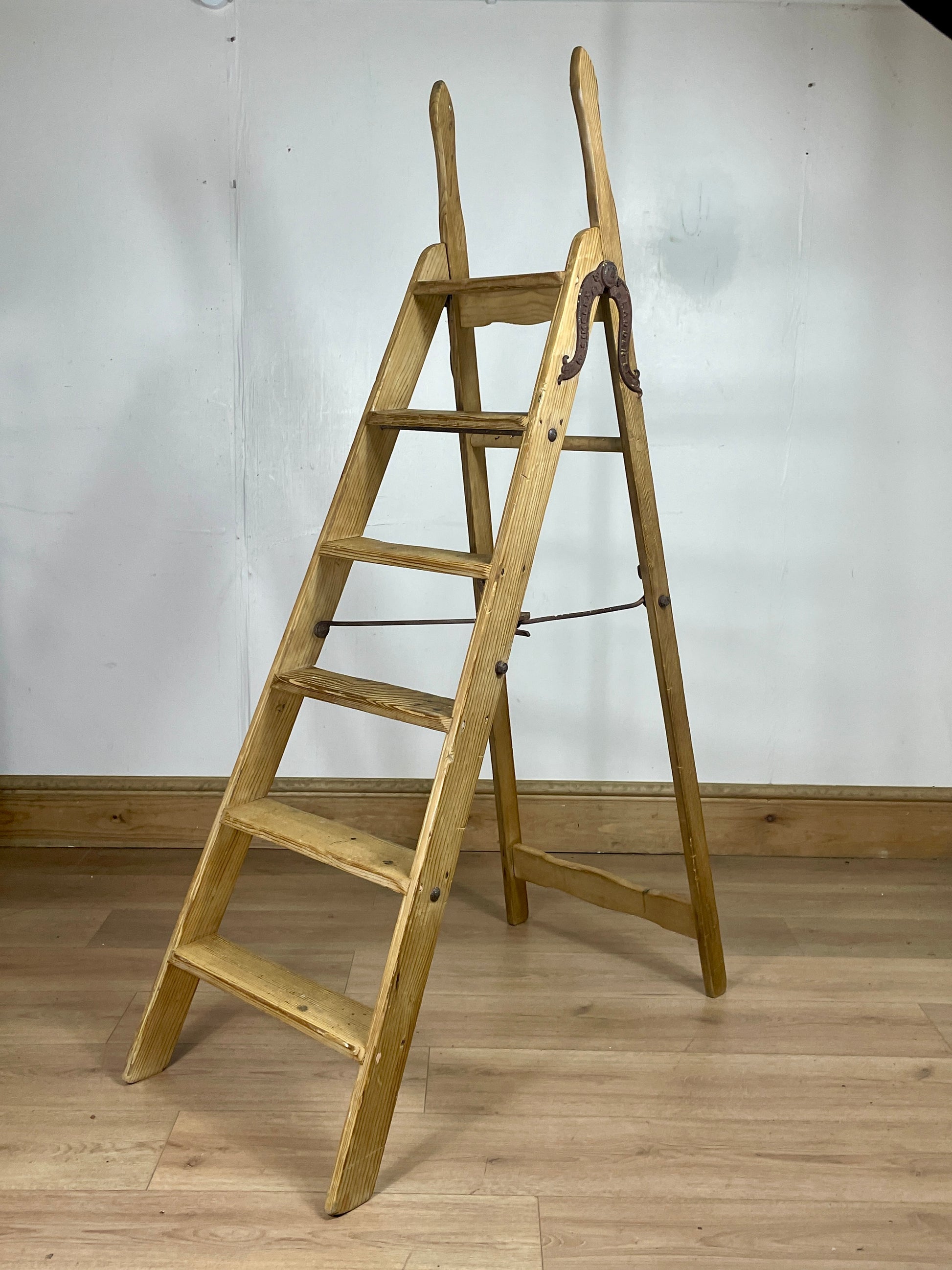Wooden ladder against a white wall on a wooden floor
