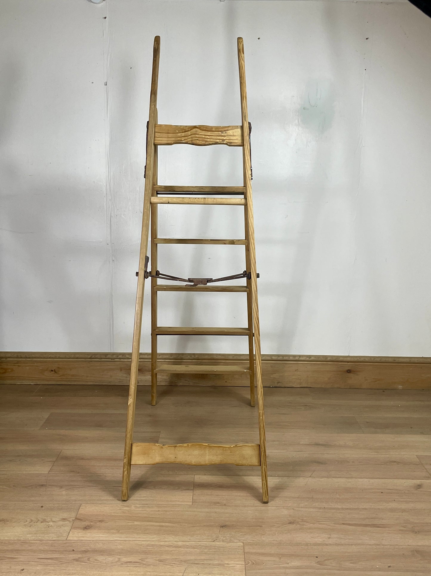 Wooden ladder against a white wall on a wooden floor