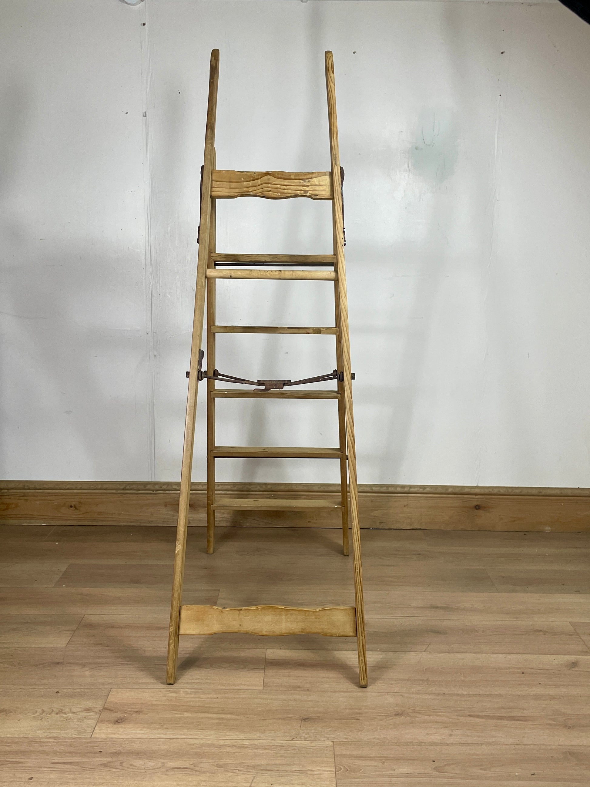 Wooden ladder against a white wall on a wooden floor