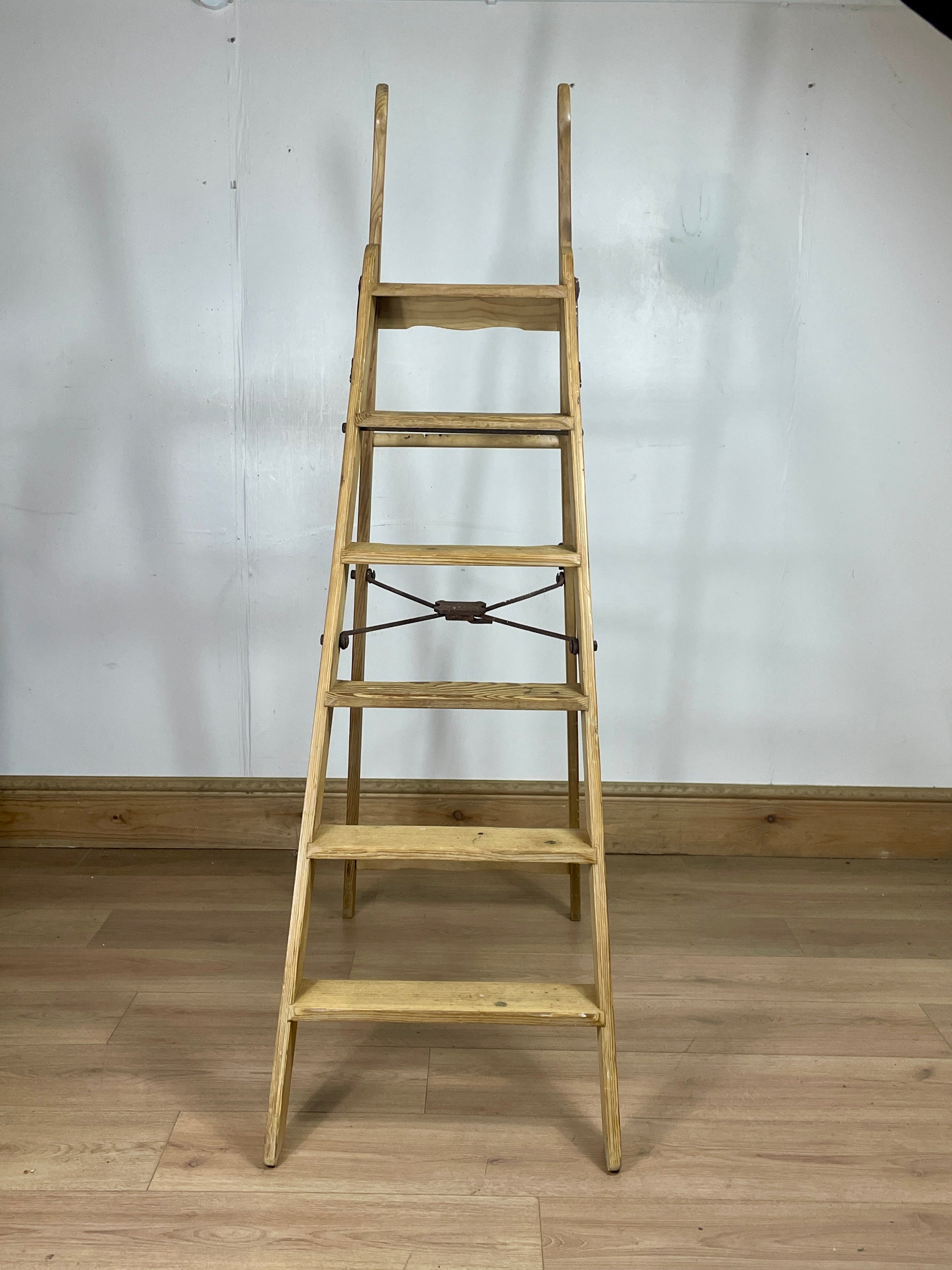 Wooden ladder against a white wall on a wooden floor