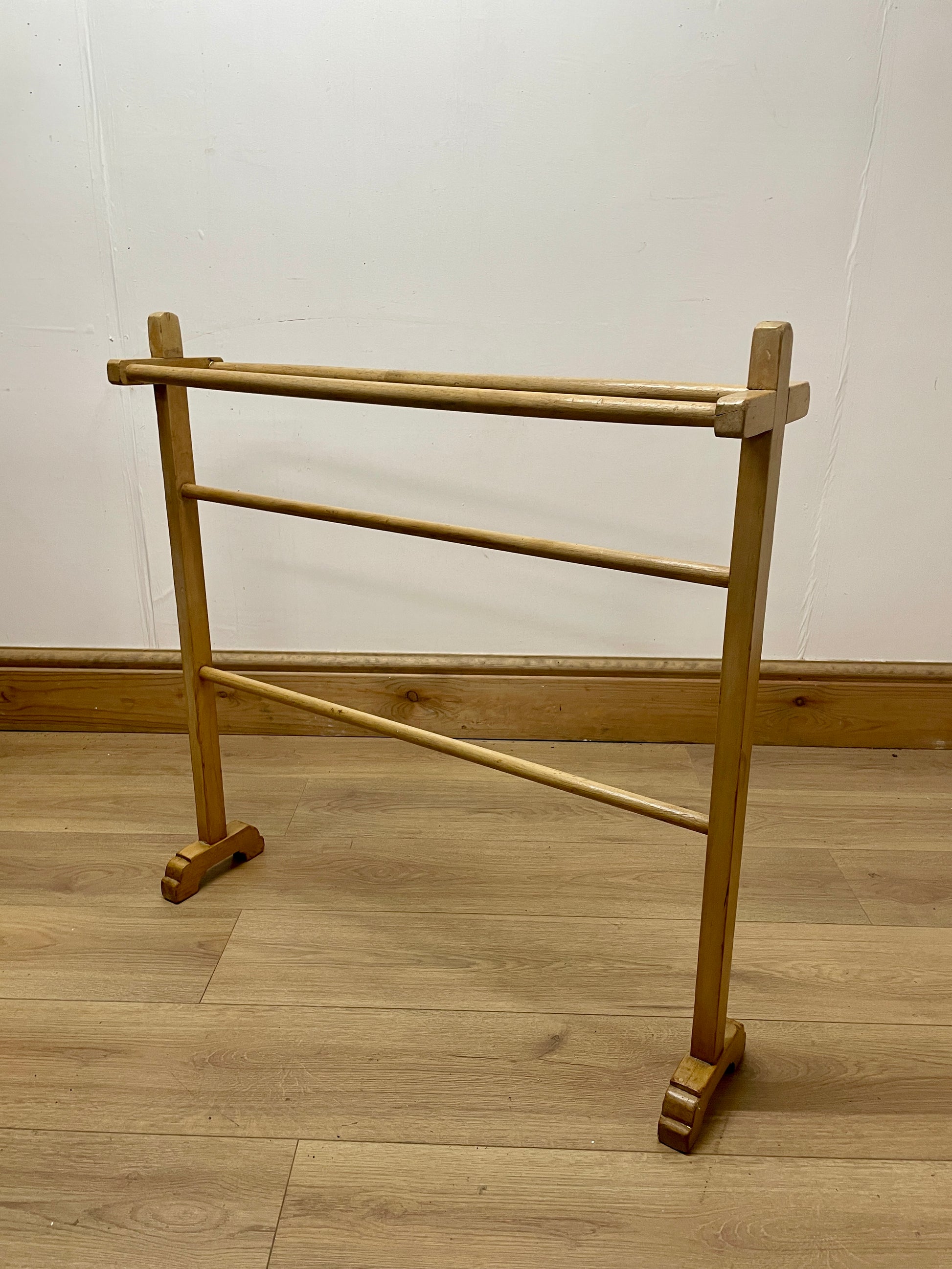 Wooden towel rack on a wooden floor with a white wall background
