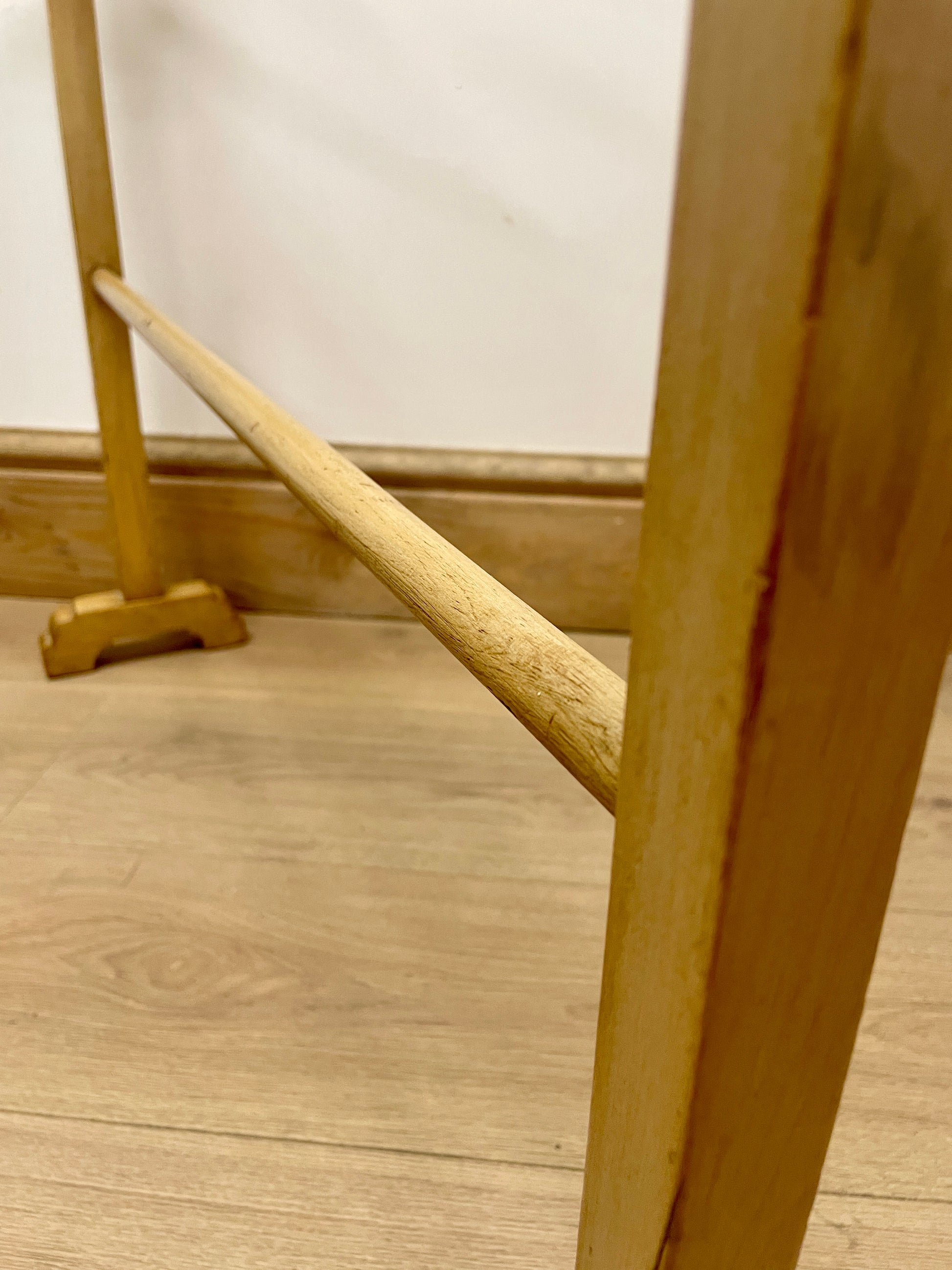 Wooden coat rack on a wooden floor with a white wall background