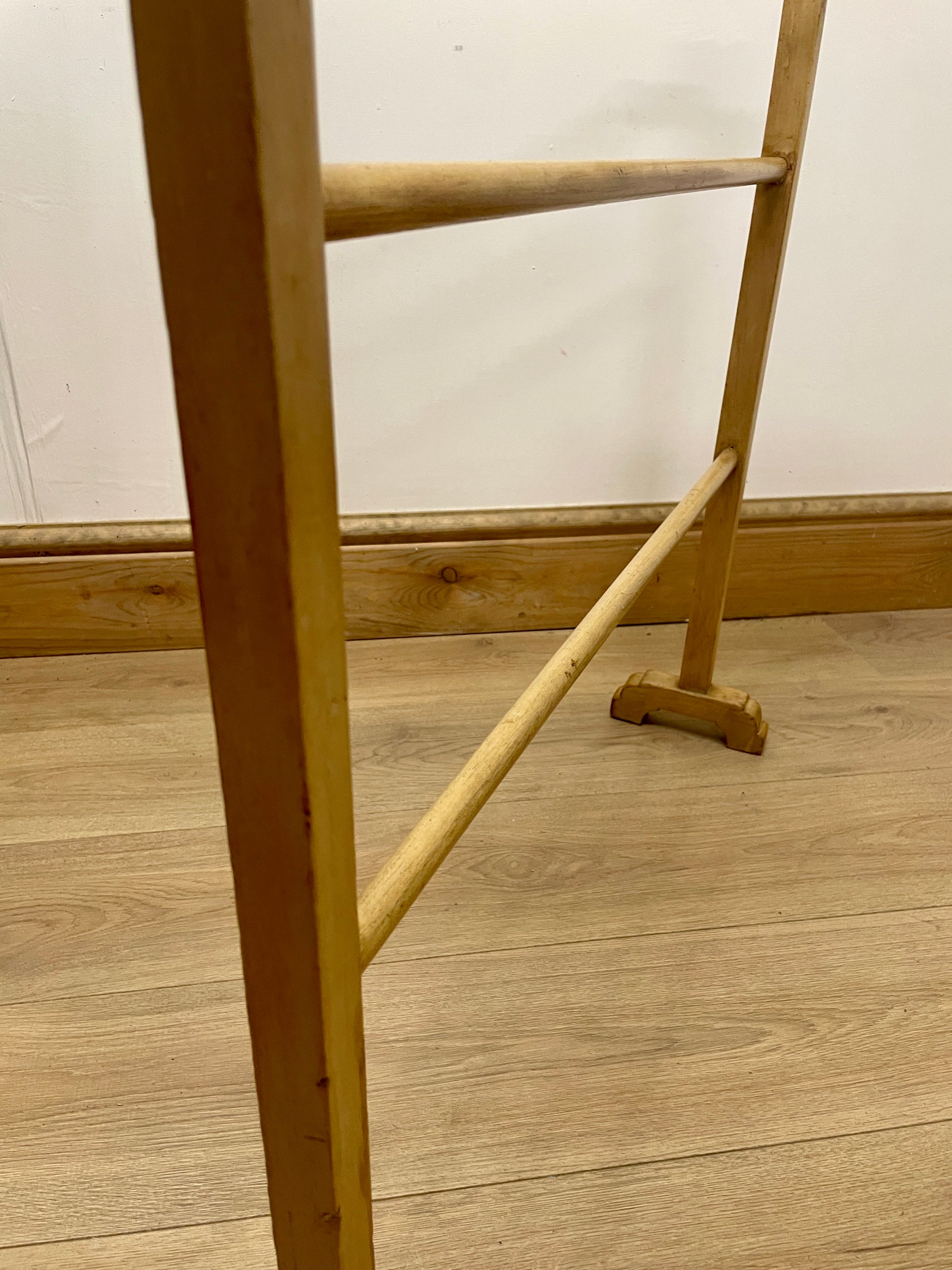 Wooden ladder on a wooden floor with a white wall background