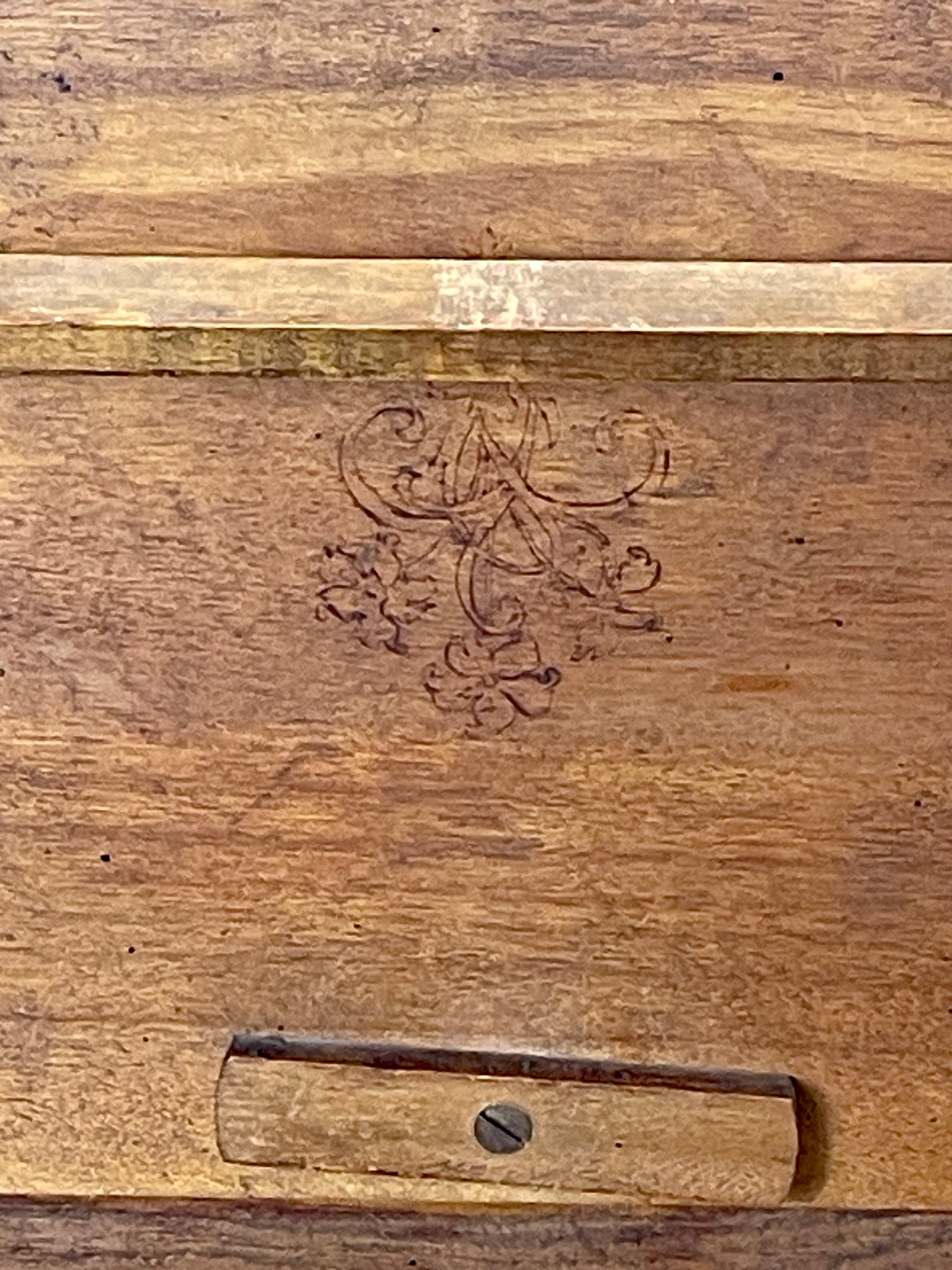 Wooden surface with an engraved design and a metal bracket.