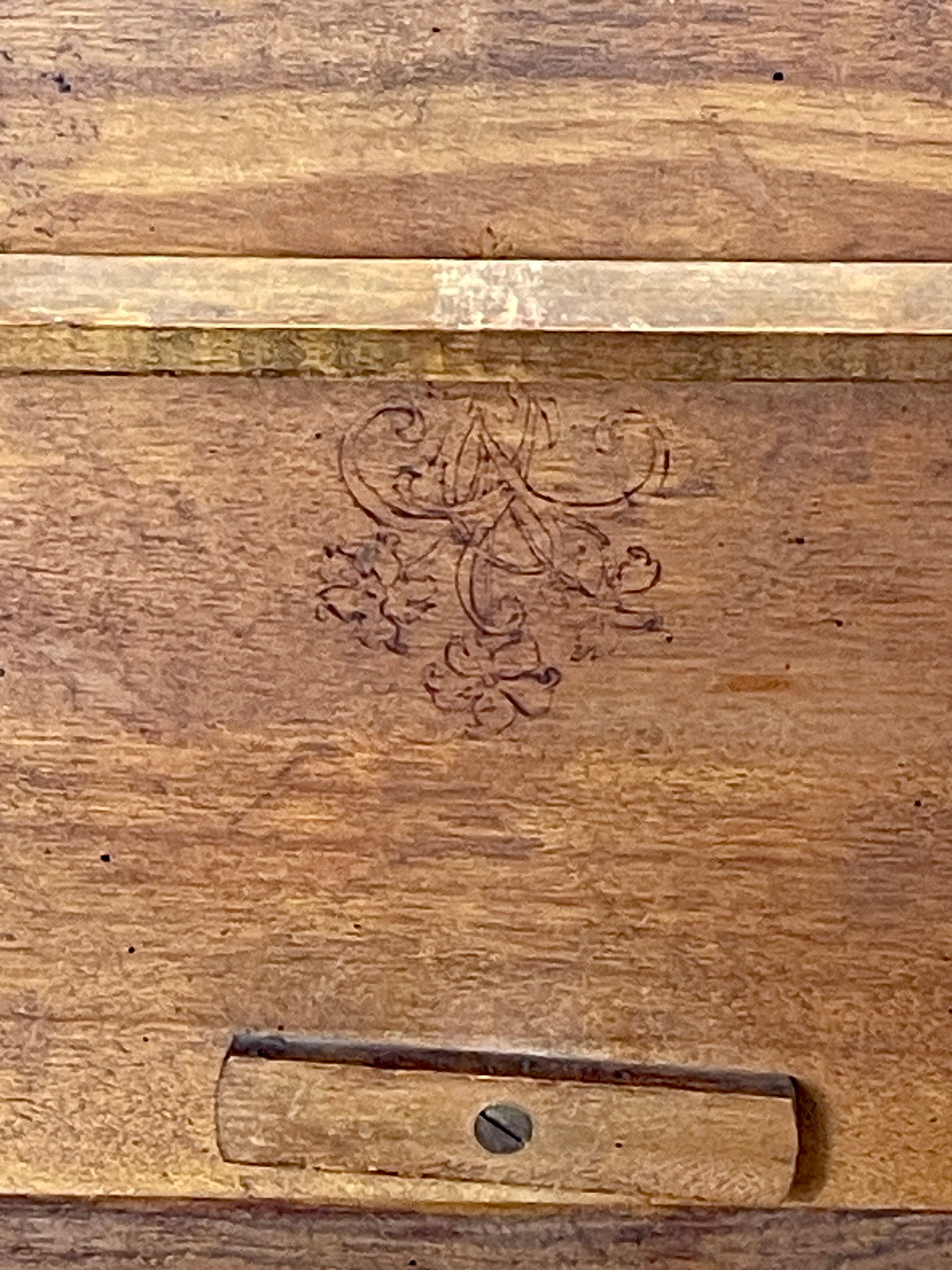 Wooden surface with an engraved design and a metal bracket.