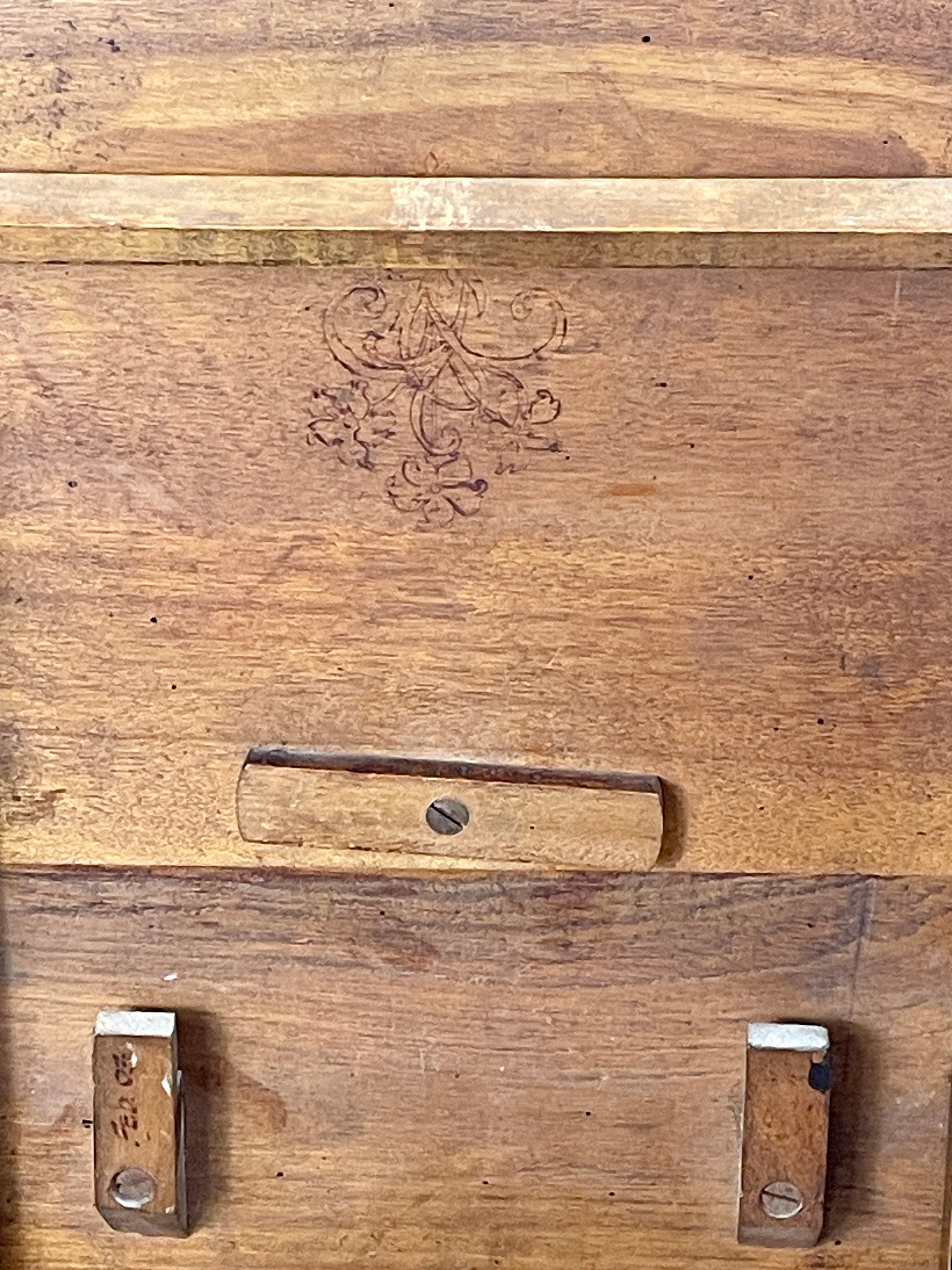 Close-up of a wooden surface with engraved design and metal fixtures.