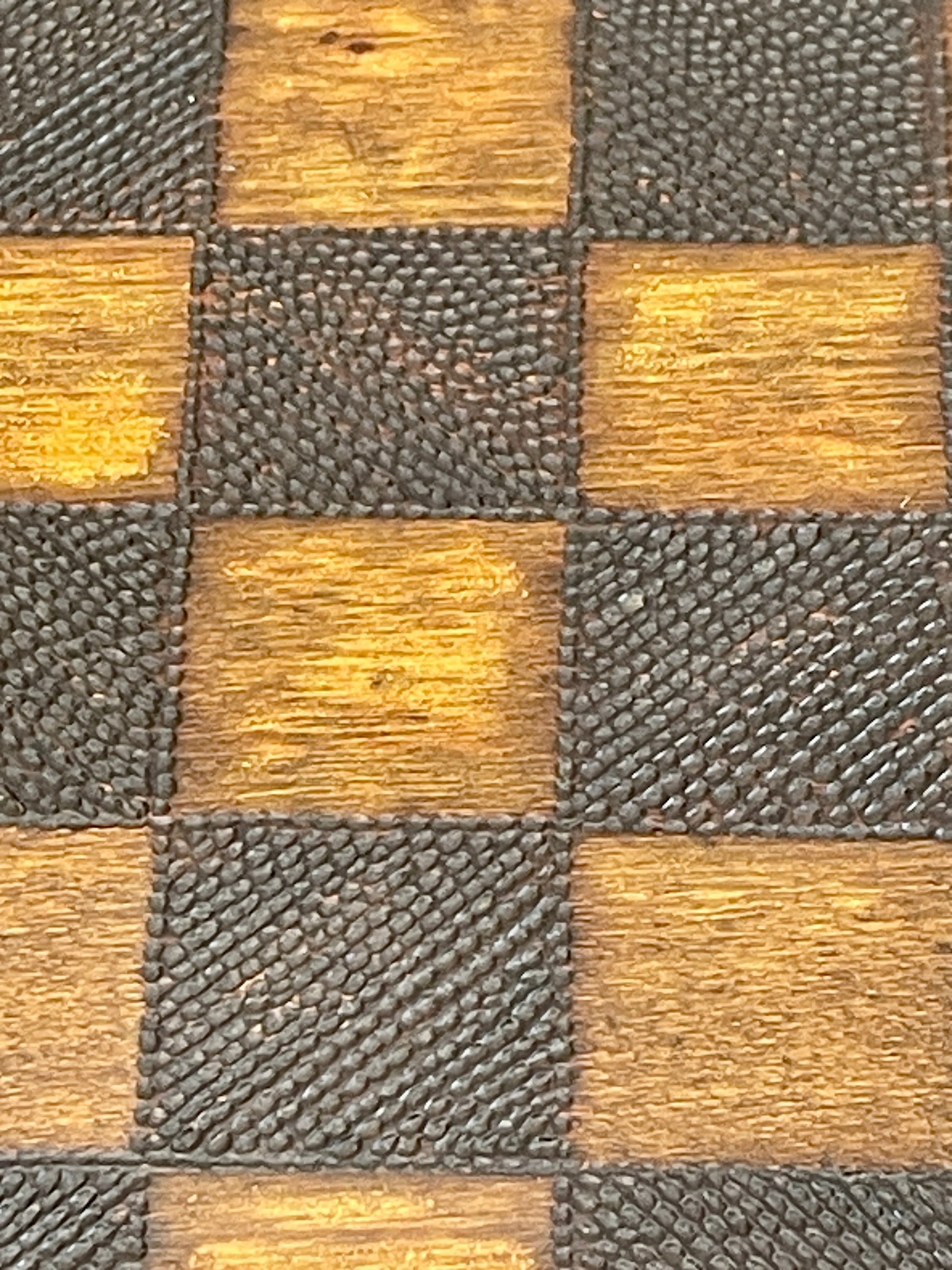 Checkered pattern of brown and gray squares on a textured surface