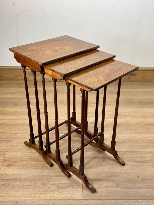 Set of three wooden nesting tables on a wooden floor with a white wall background