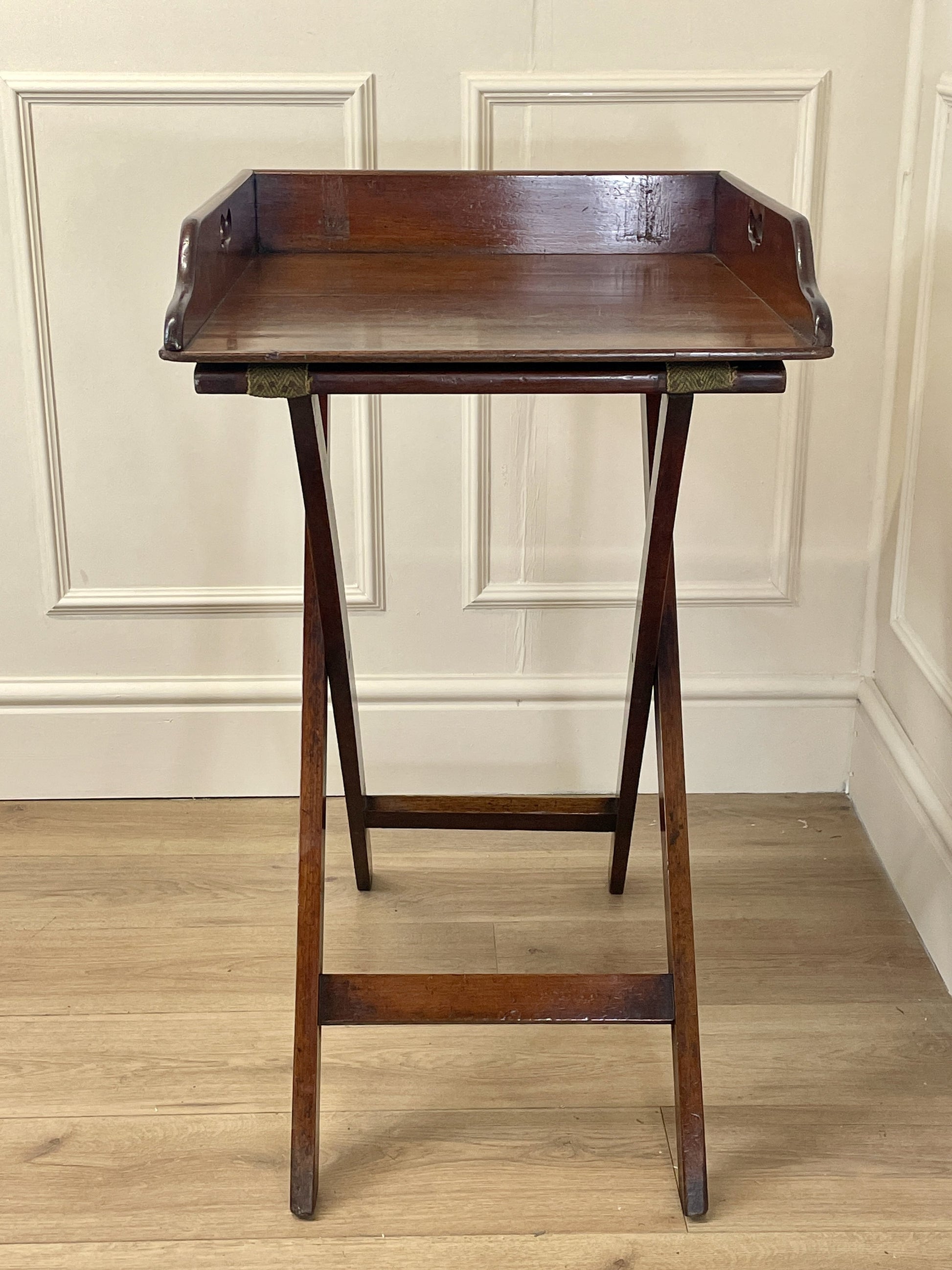 Wooden stand with a tray on a wooden floor against a white wall.