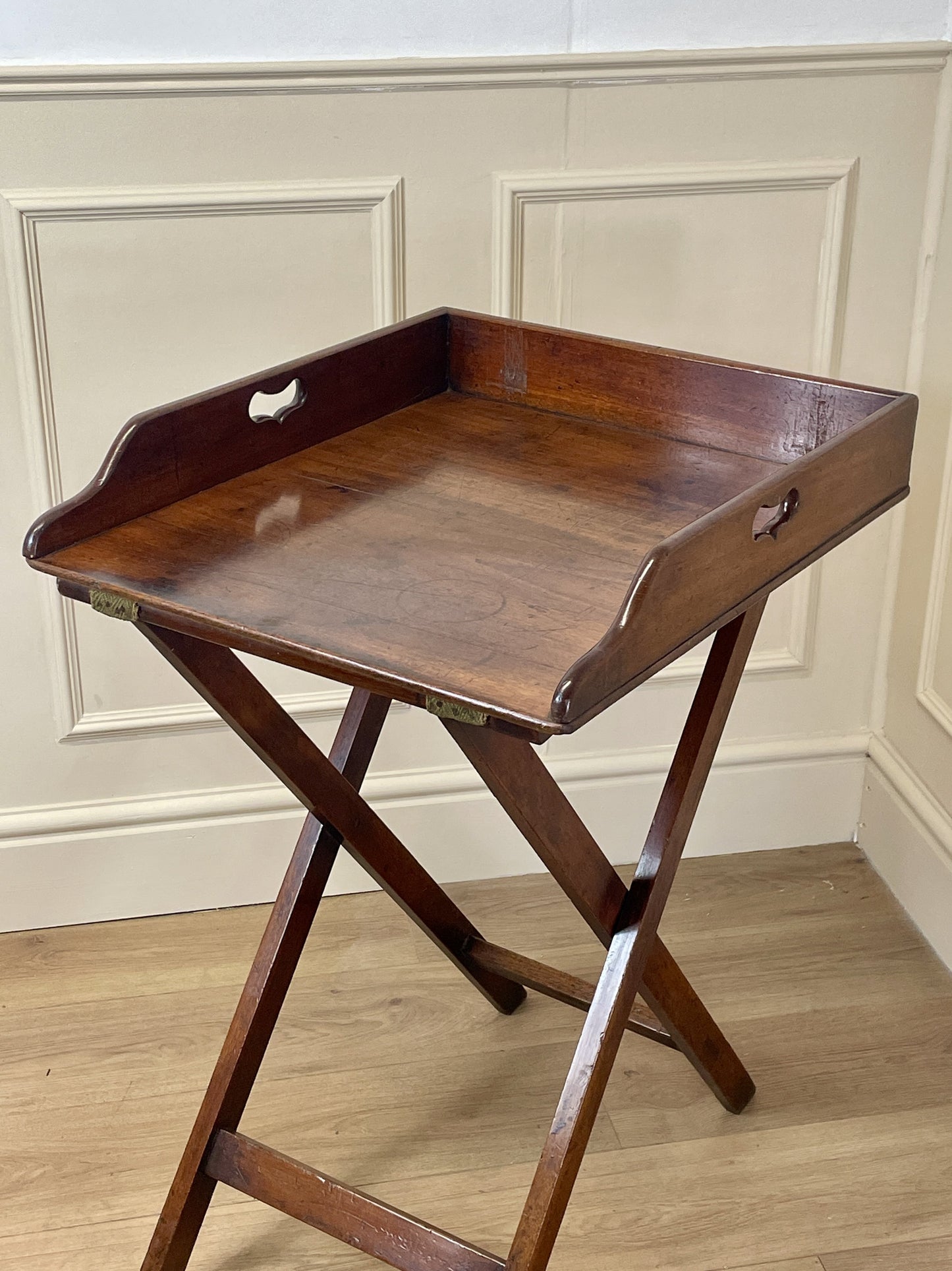 Wooden tray table against a beige wall.