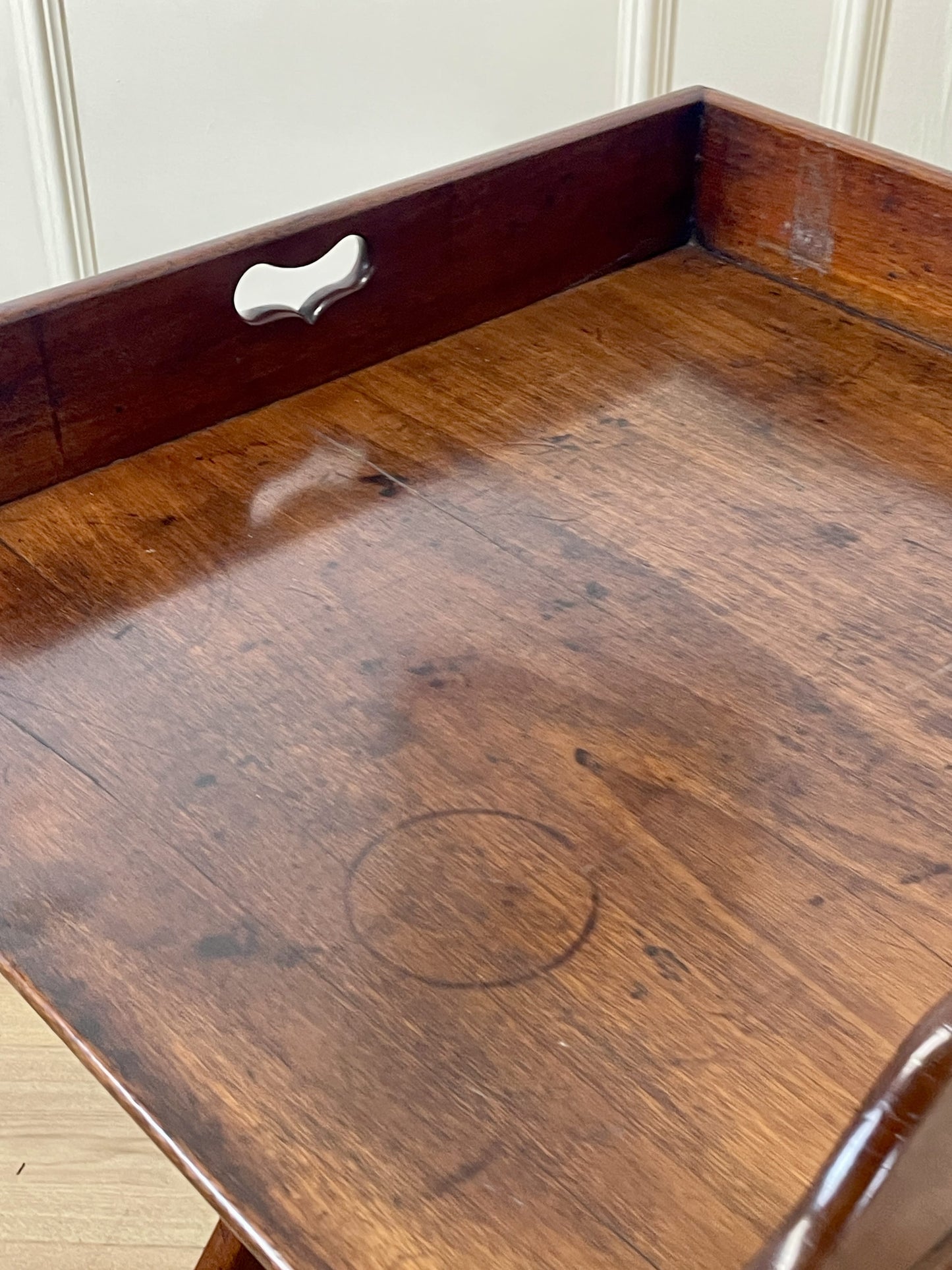 Wooden tray with a metal handle on a wooden surface