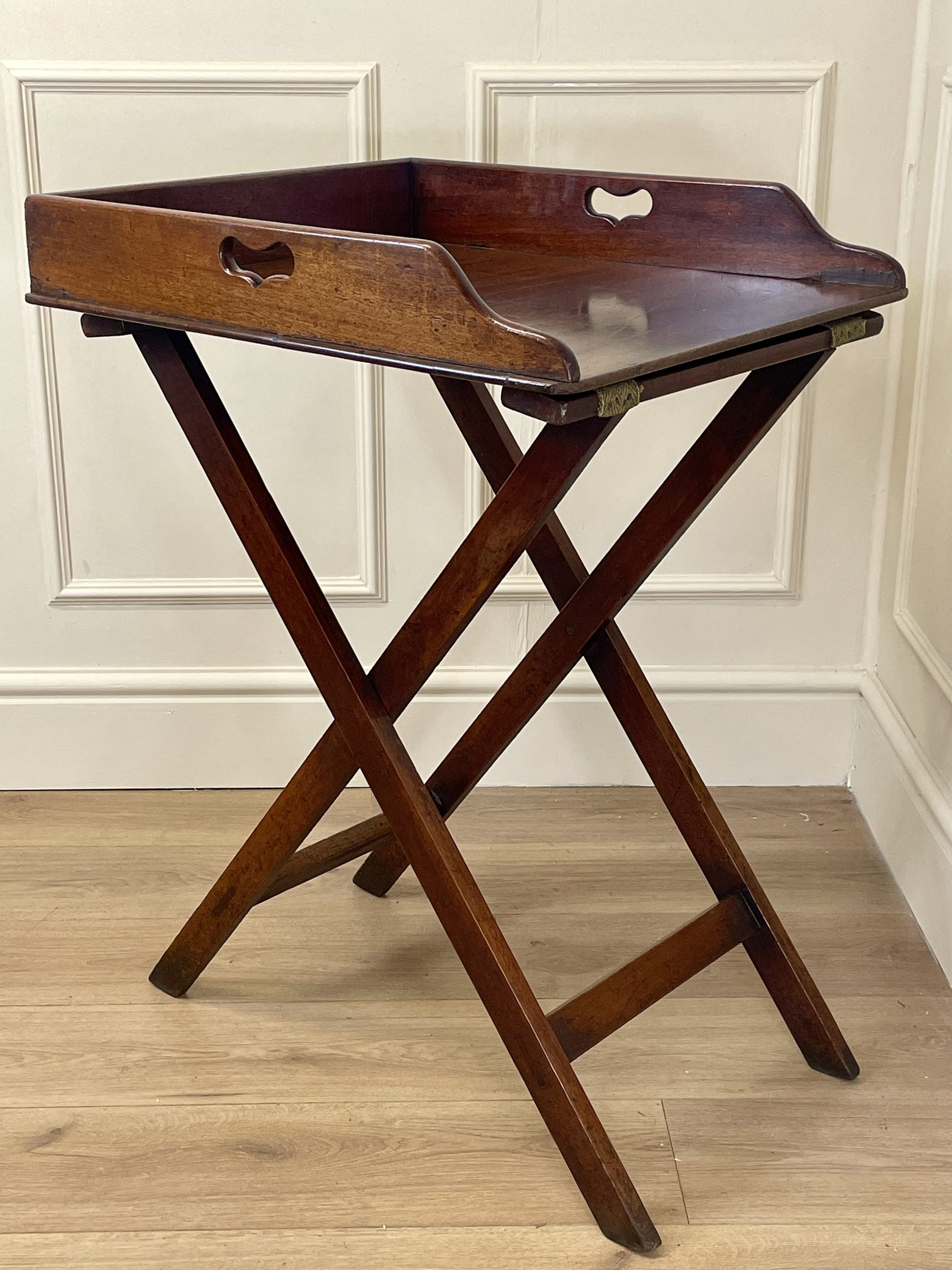 Wooden tray table with a hexagonal tray on a wooden floor.