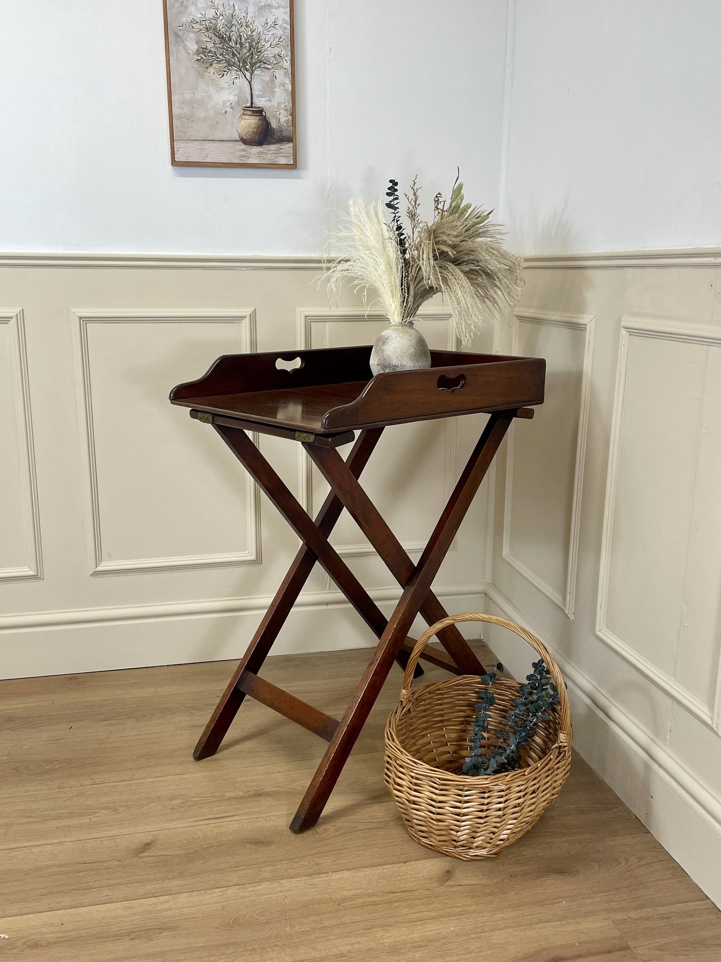 Wooden tray table with decorative items against a wall with paneling