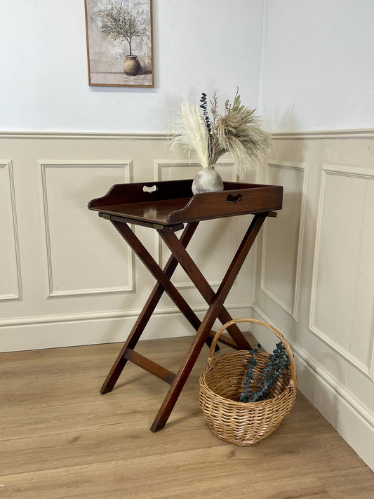 Wooden tray table with decorative items against a wall with paneling