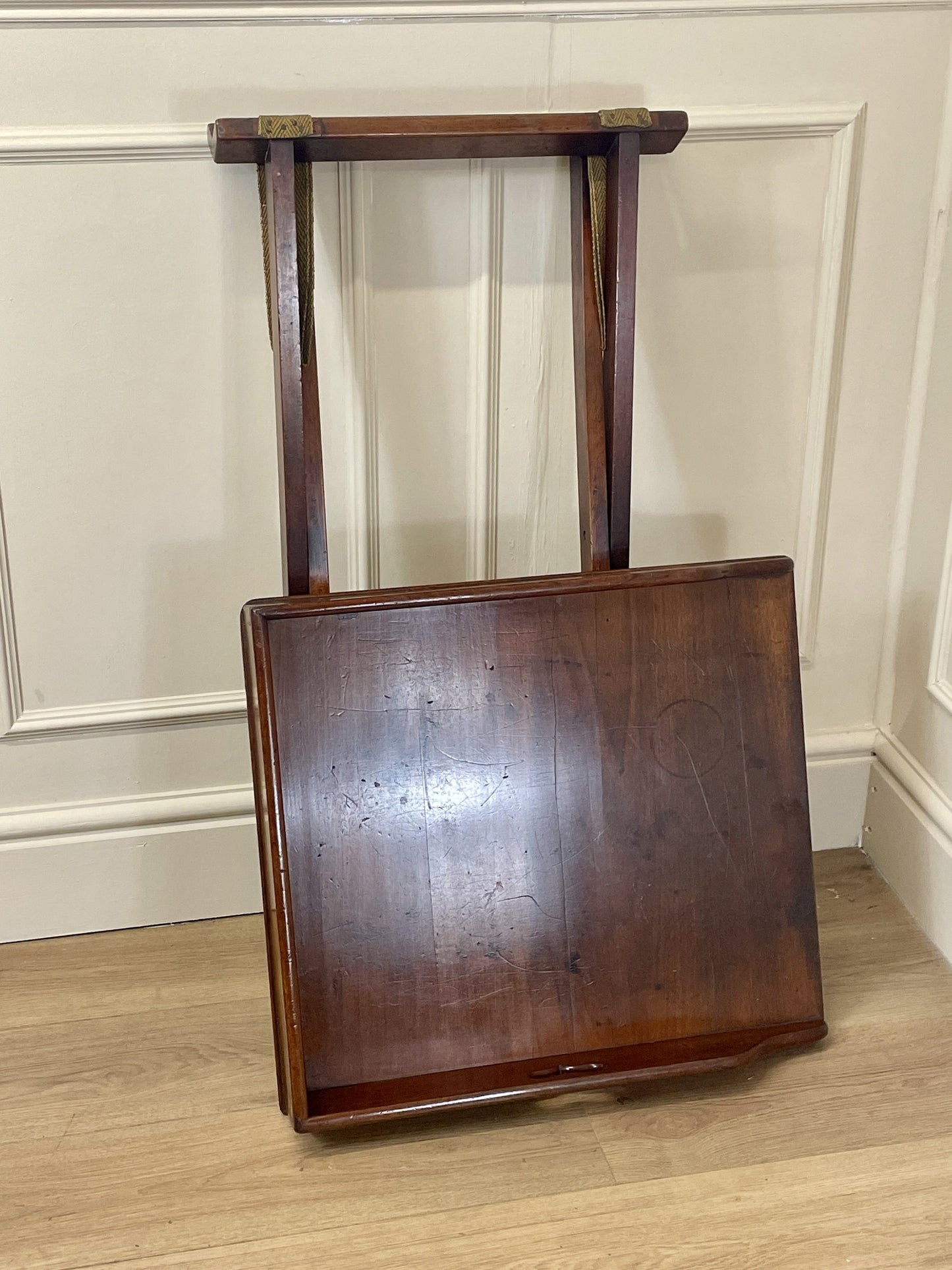 Wooden chair with a straight back against a beige wall.