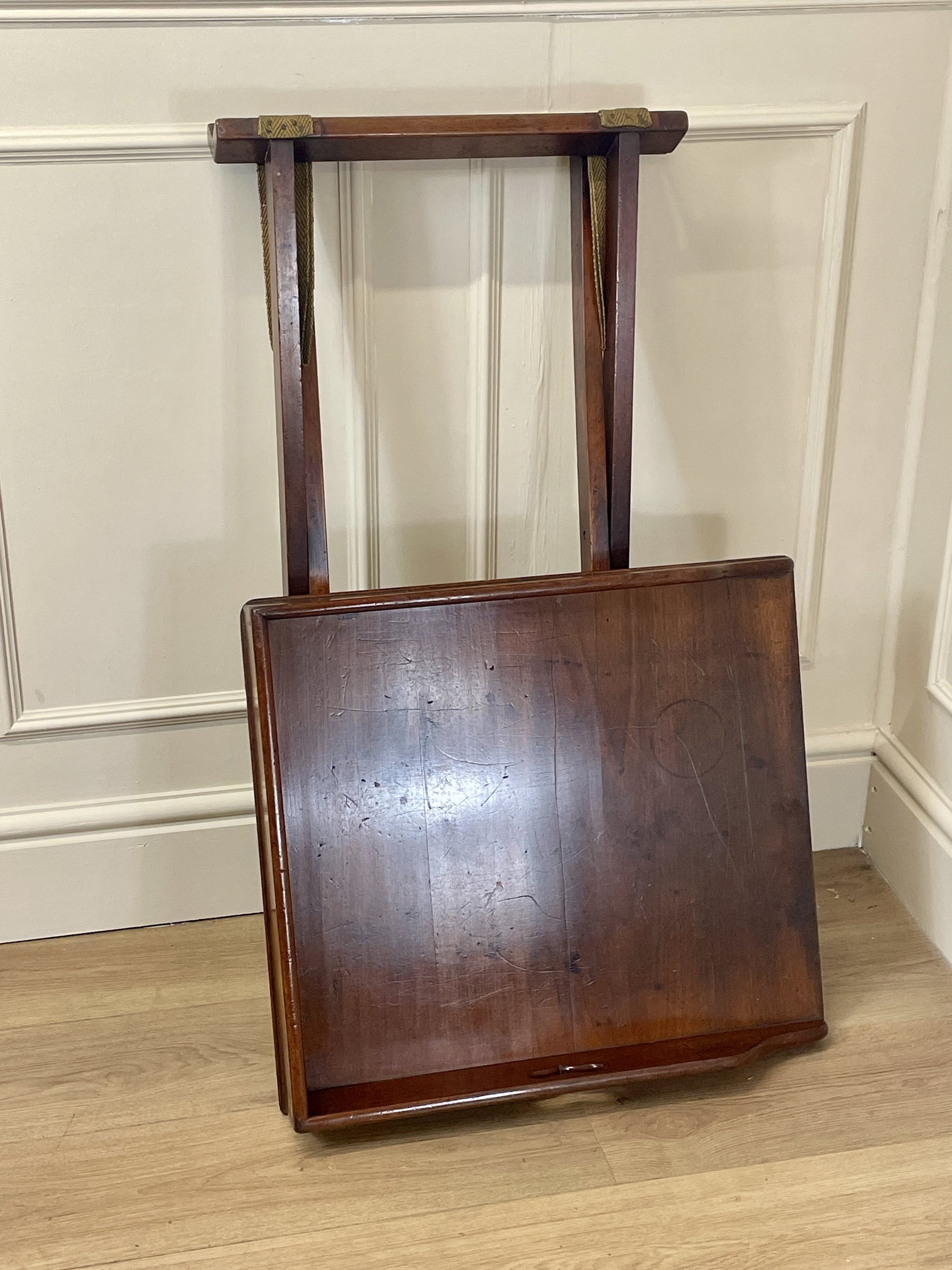 Wooden chair with a straight back against a beige wall.