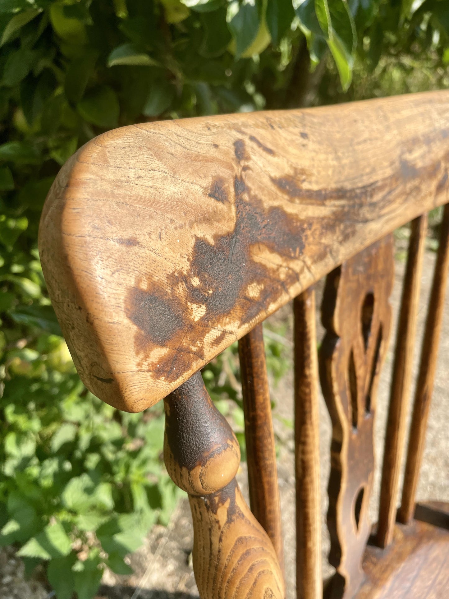 Close-up of a wooden chair with intricate carvings against a blurred green background