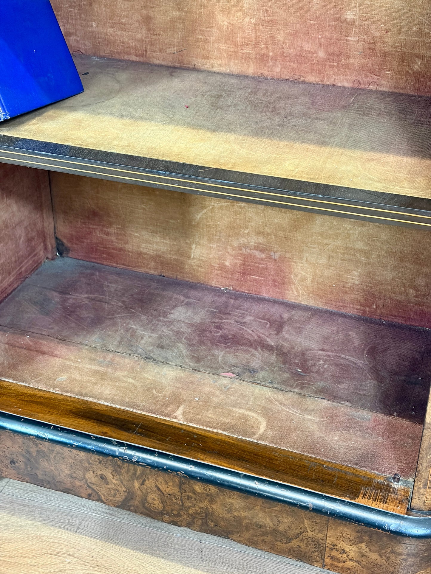 Wooden bookshelf with three shelves showing signs of wear.